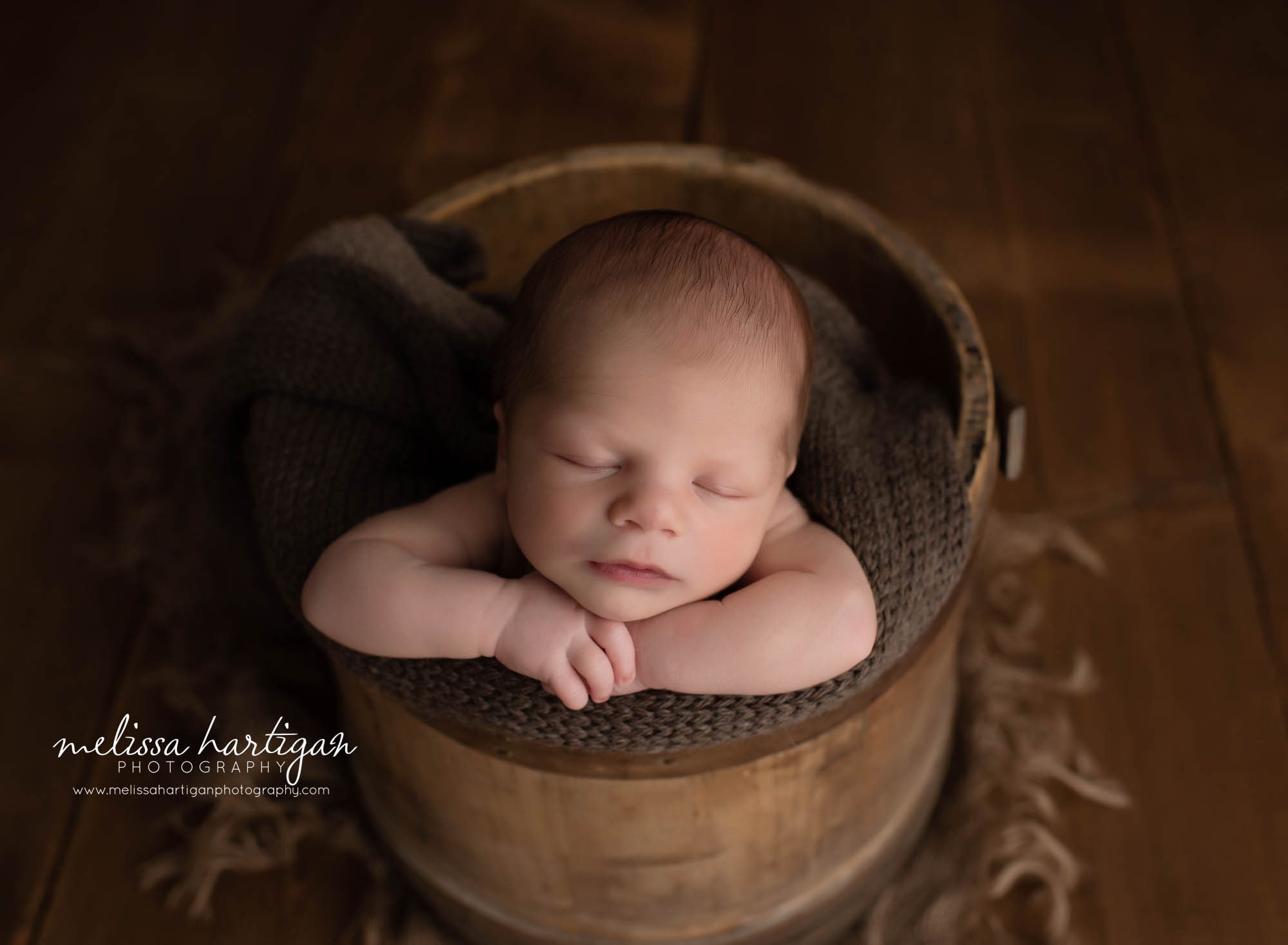 baby boy posed in rustic bucket with brown wrap