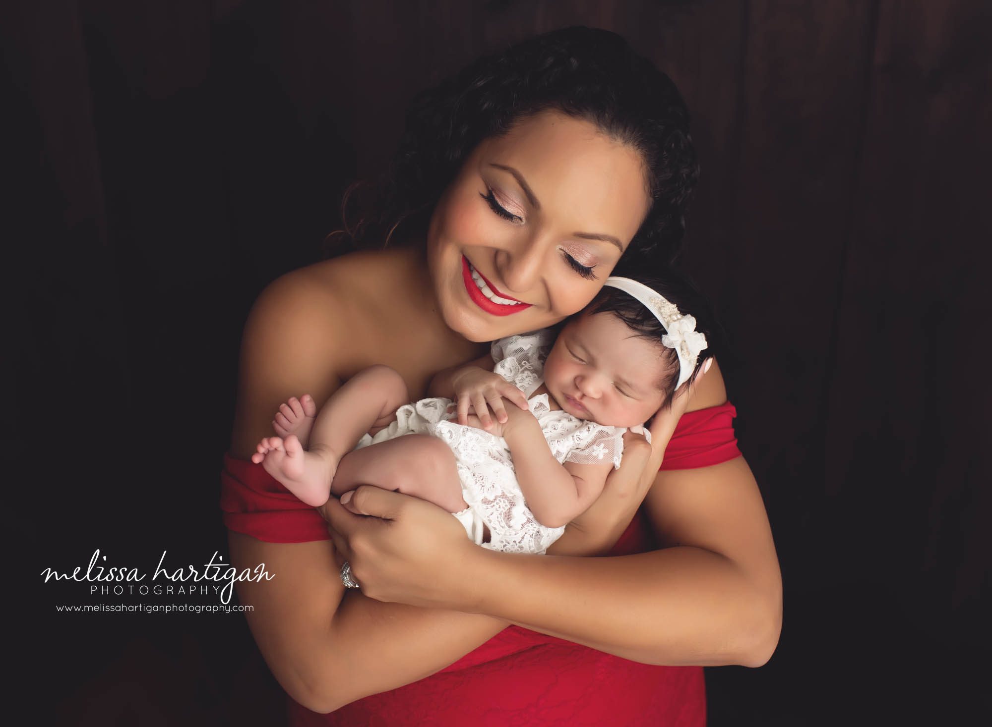 mom holding baby girl with her eyes closed smiling