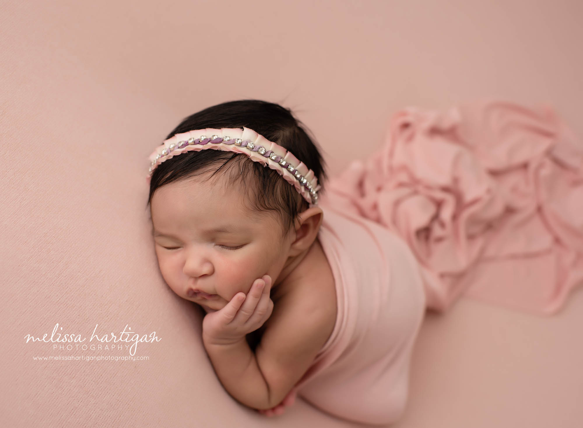 Baby girl with hands on her cheek wearing pink jeweled headband