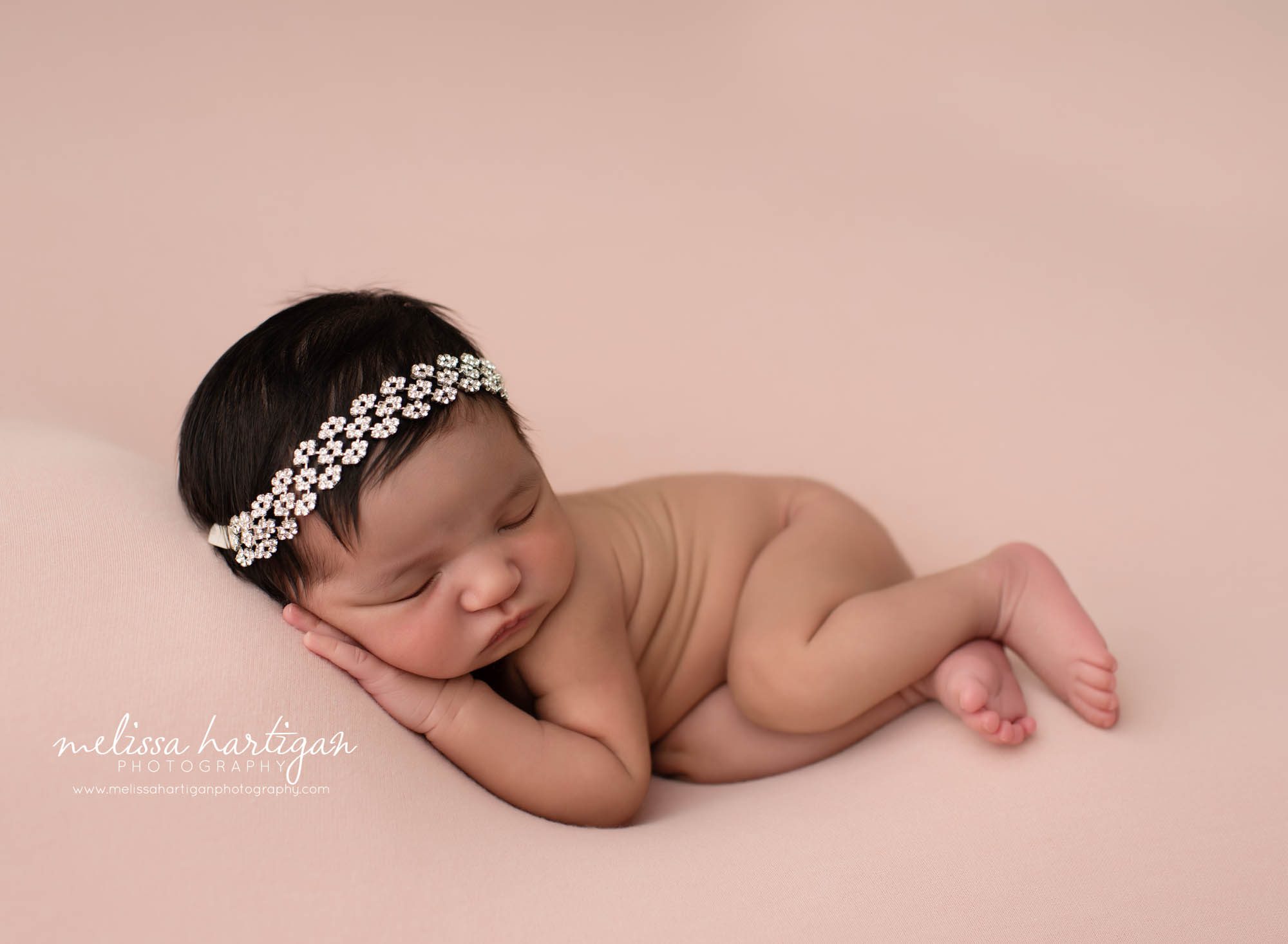 baby girl posed on her side studio newborn photography pink backdrop