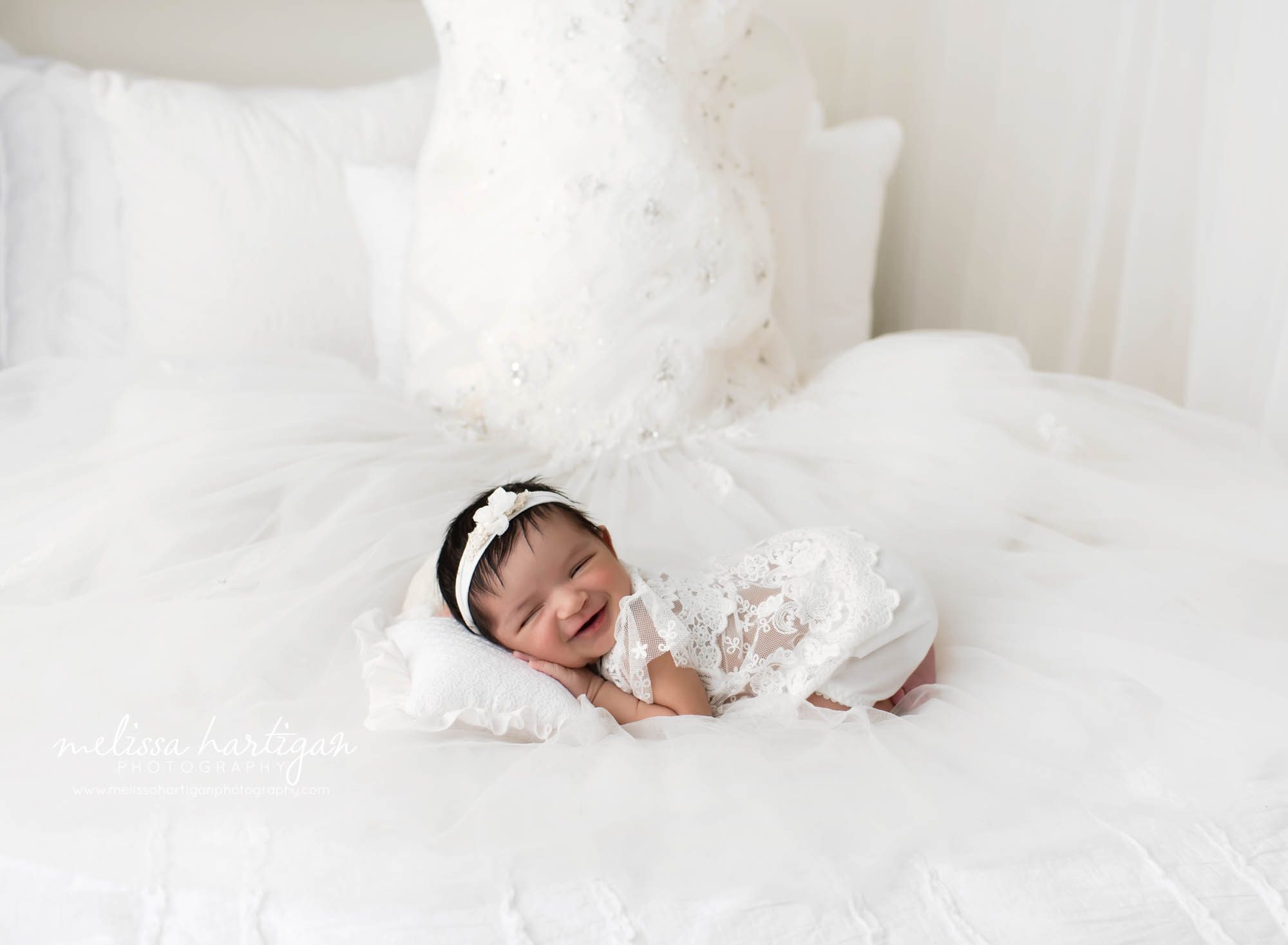 Smiling baby girl posed on moms wedding dress CT newborn Photographer
