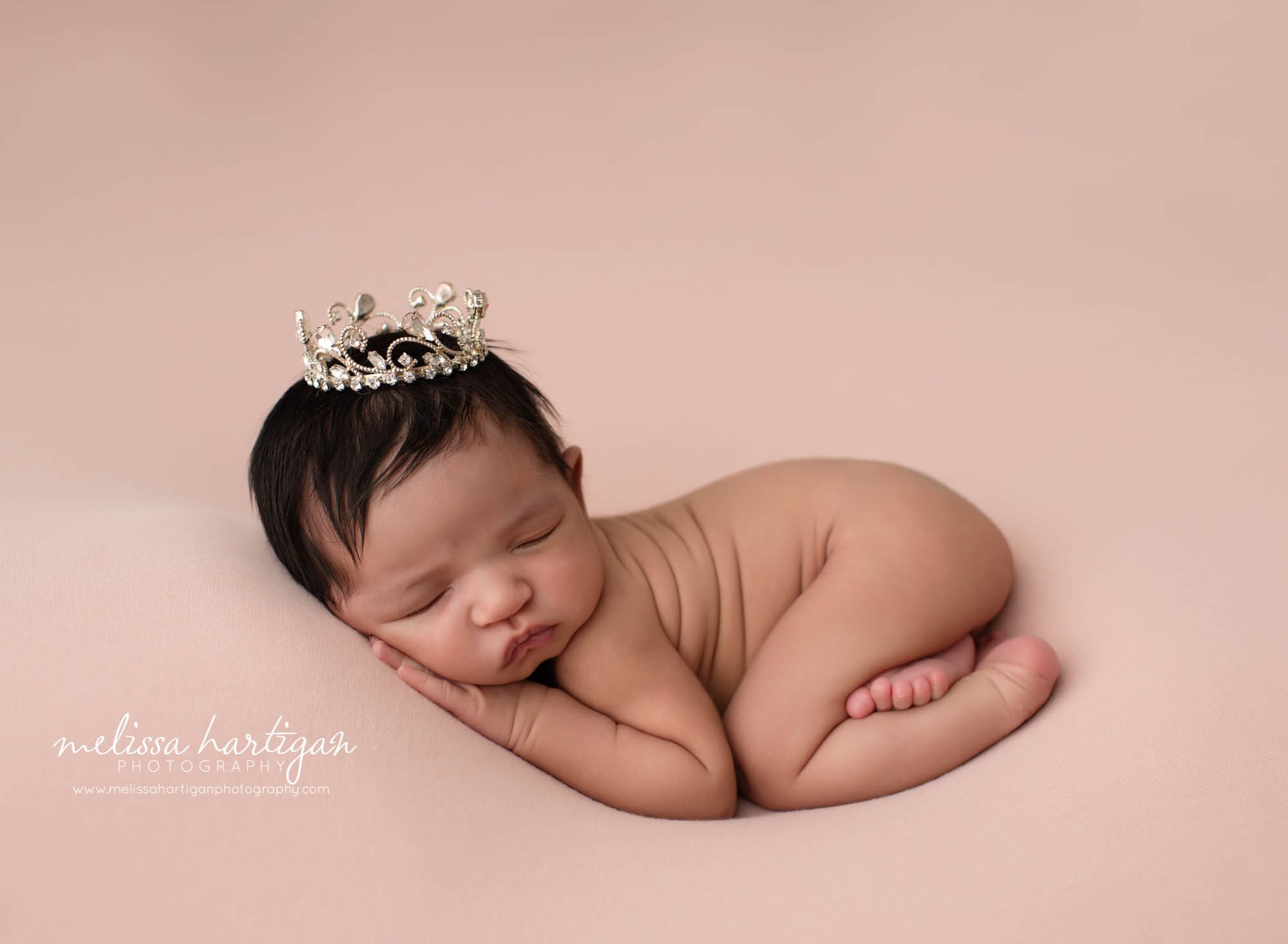 Baby girl posed in tushie up posed with jeweled newborn crown prop