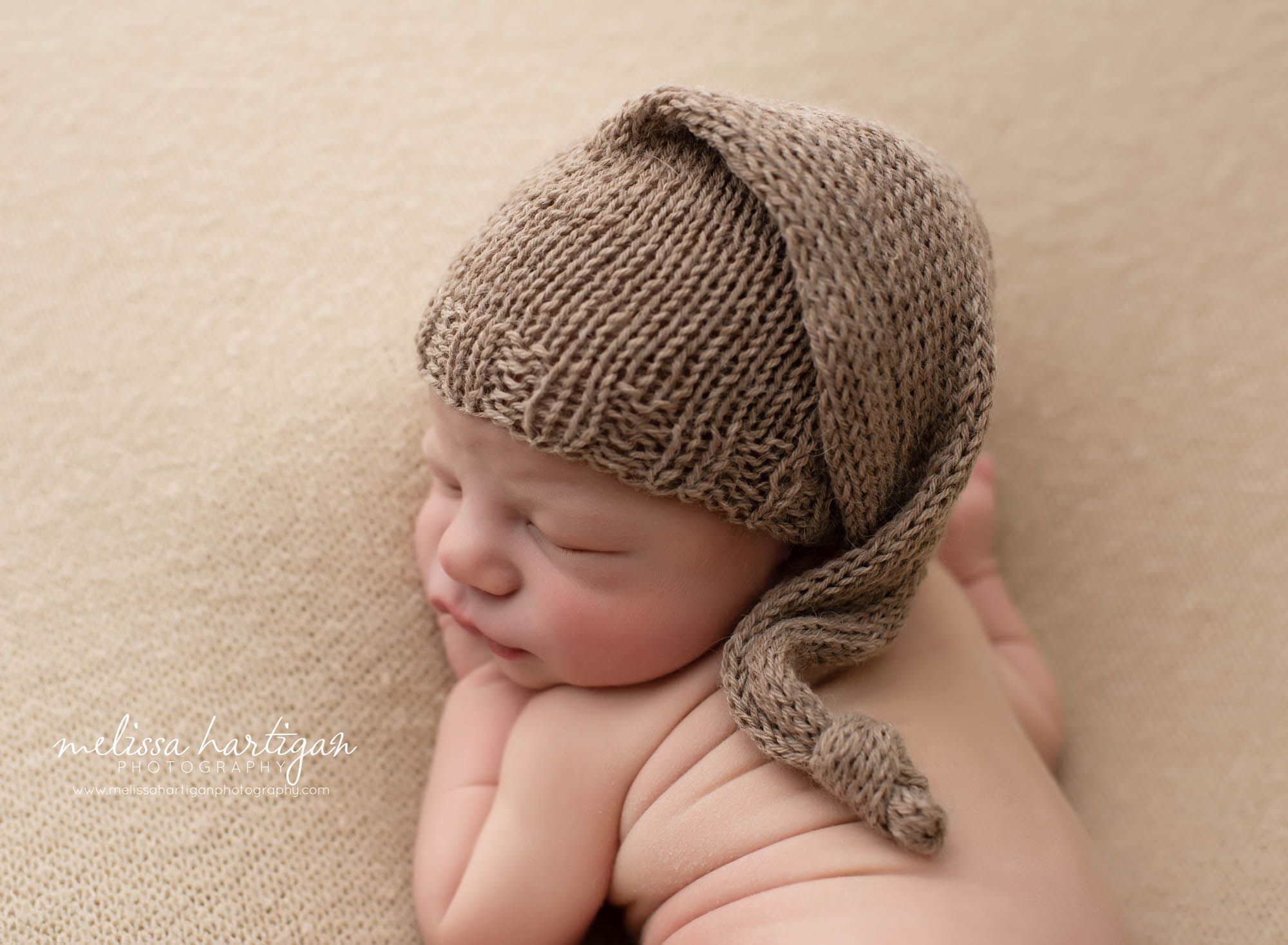 baby boy posed on tummy with back rolls wearing brown knitted sleepy cap ct newborn photography