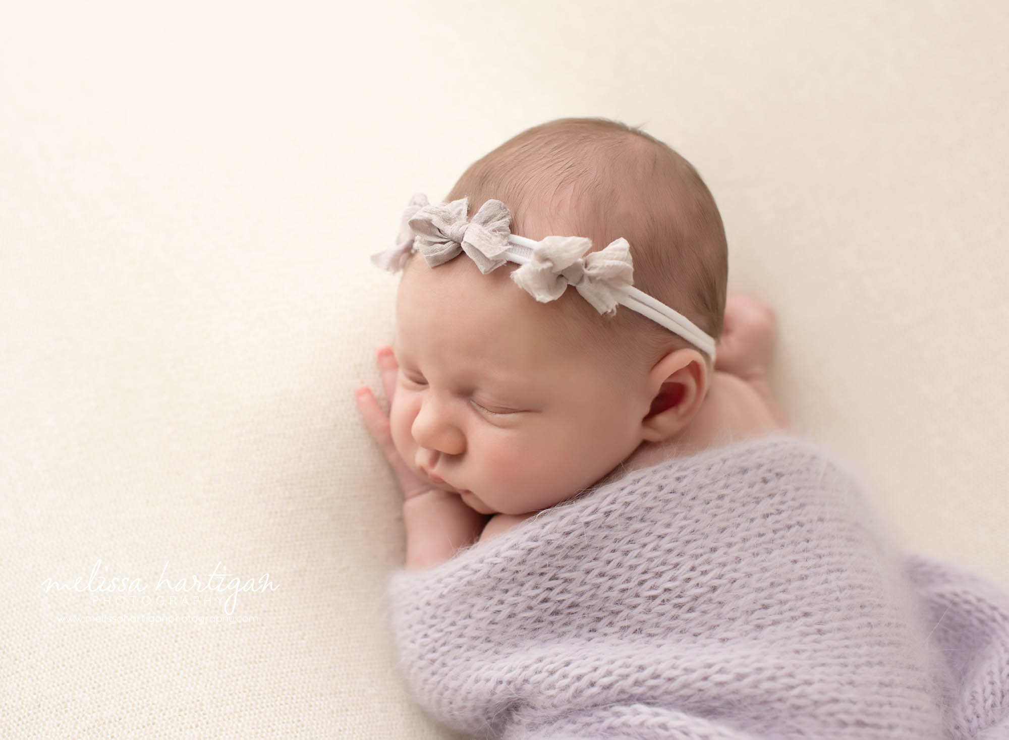 baby girl posed on tummy with light purple knitted wrap