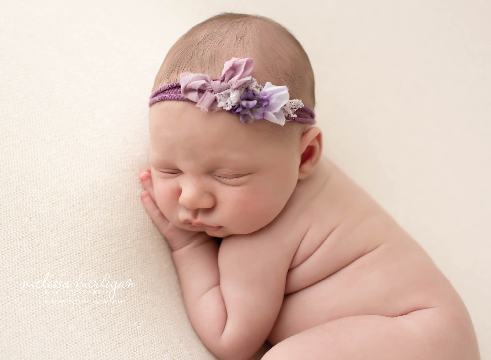 baby girl posed on side and cream colored blanket with purple headband newborn Photographers CT