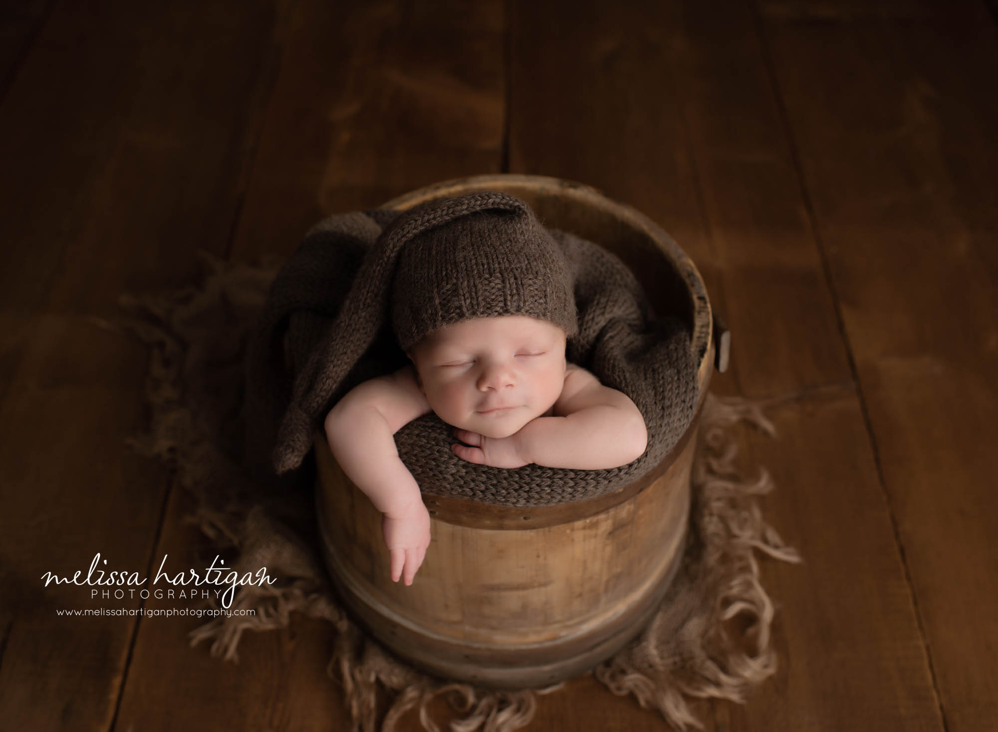 baby boy posed in rustic bucket with arm hanging down