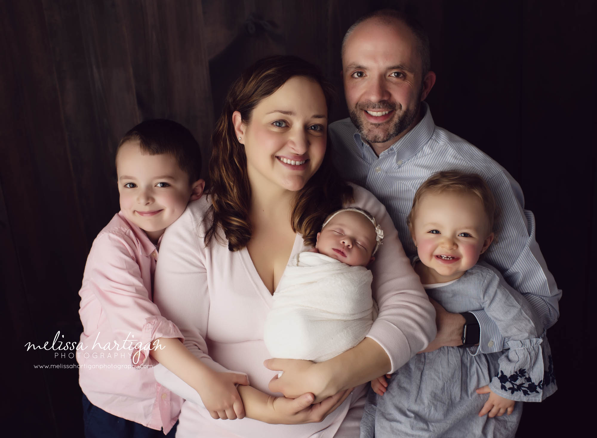 family of five newborn photography studio pose dad mom brother sister baby