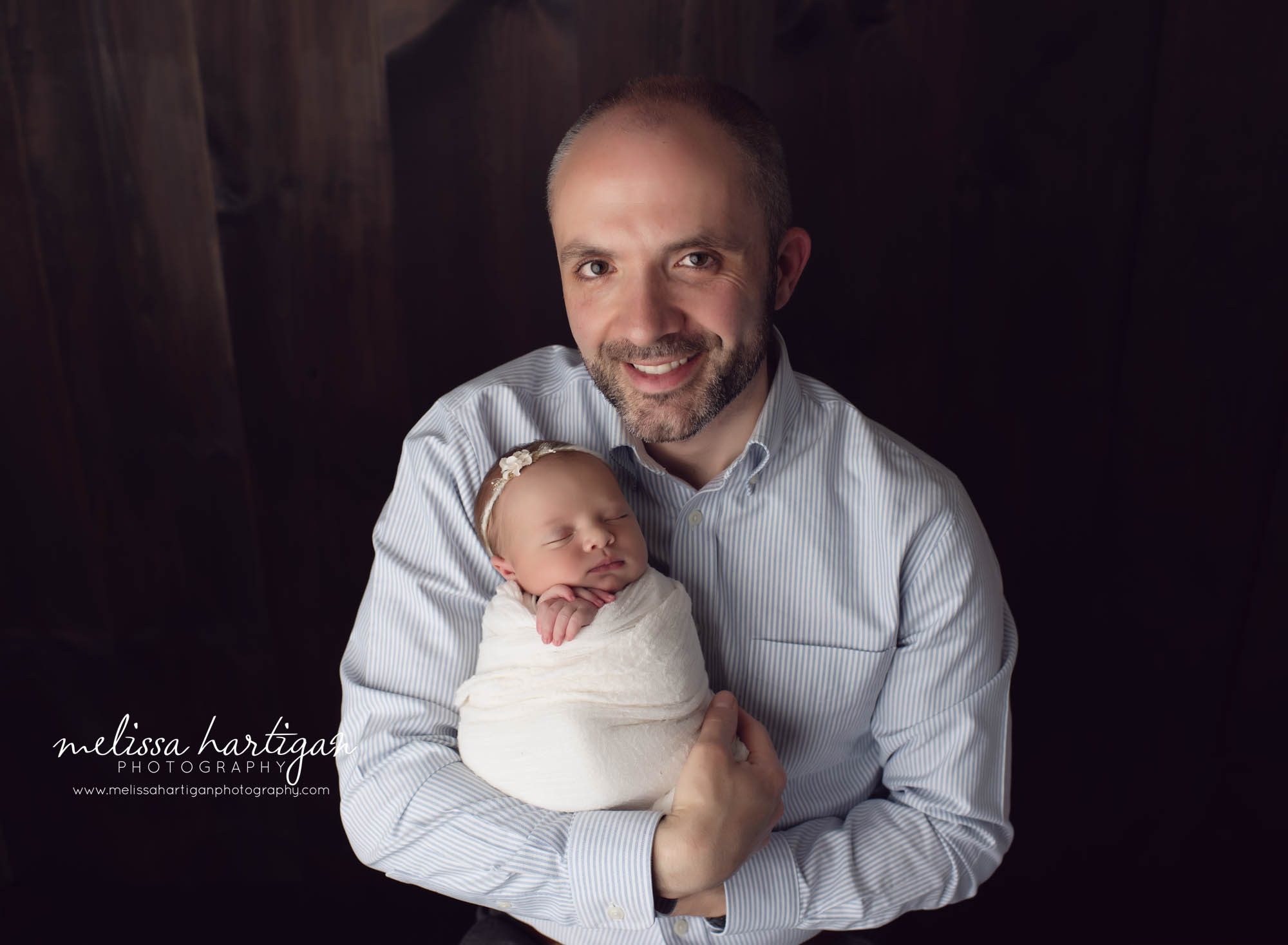 dad holding newborn baby girl studio newborn photography pose
