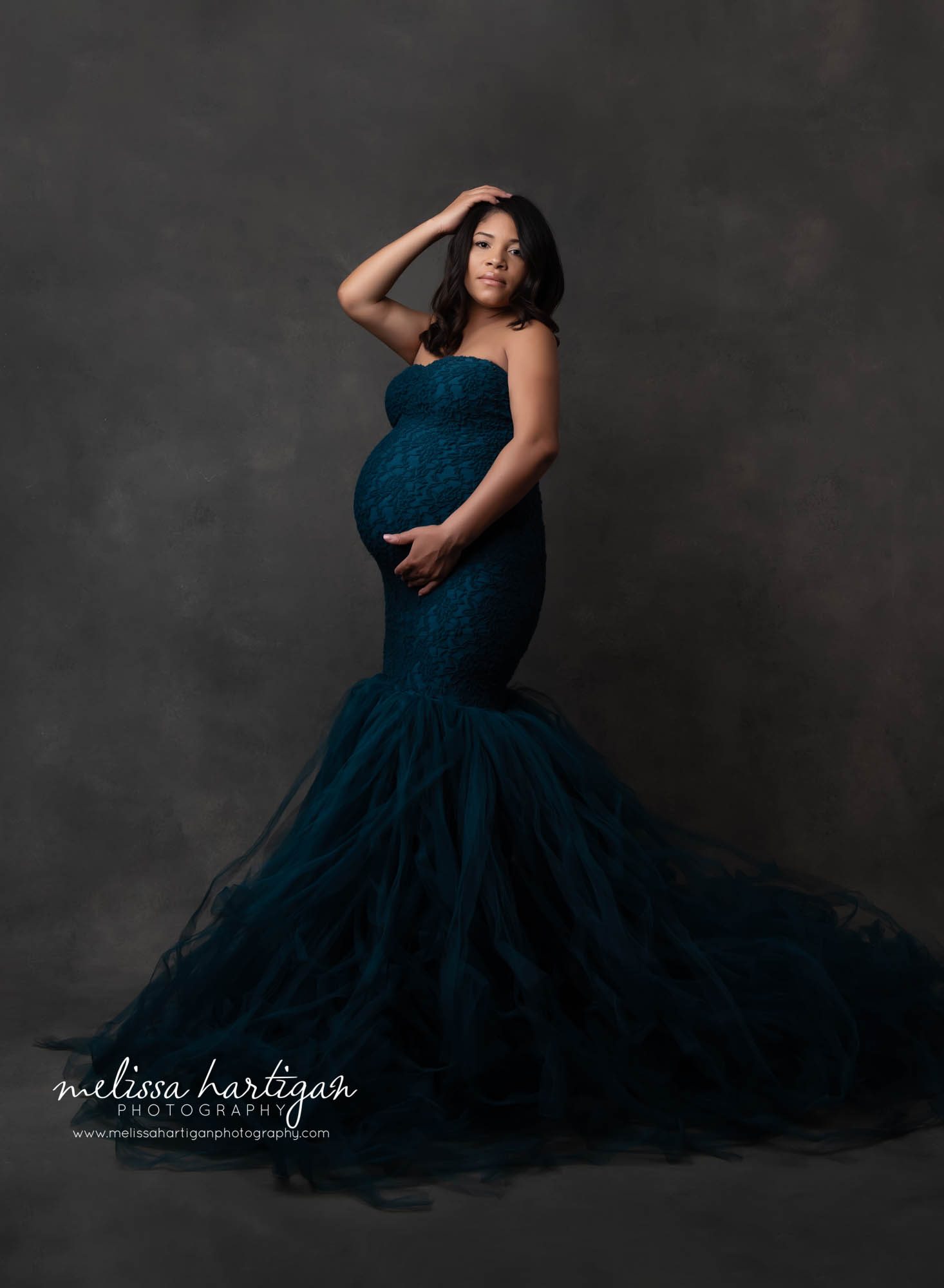 Studio maternity session expectant mother wearing teal colored form fitting mermaid style maternity dress with lace