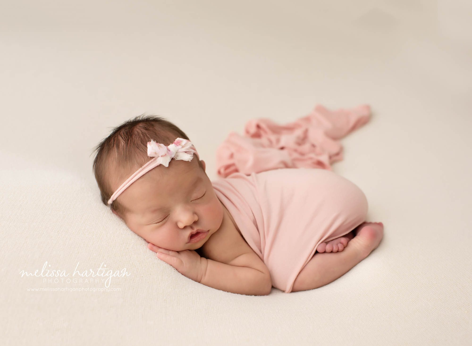 baby girl posed on tummy with hand under cheek wrapped in pink and pink bow headband ct newborn photographer