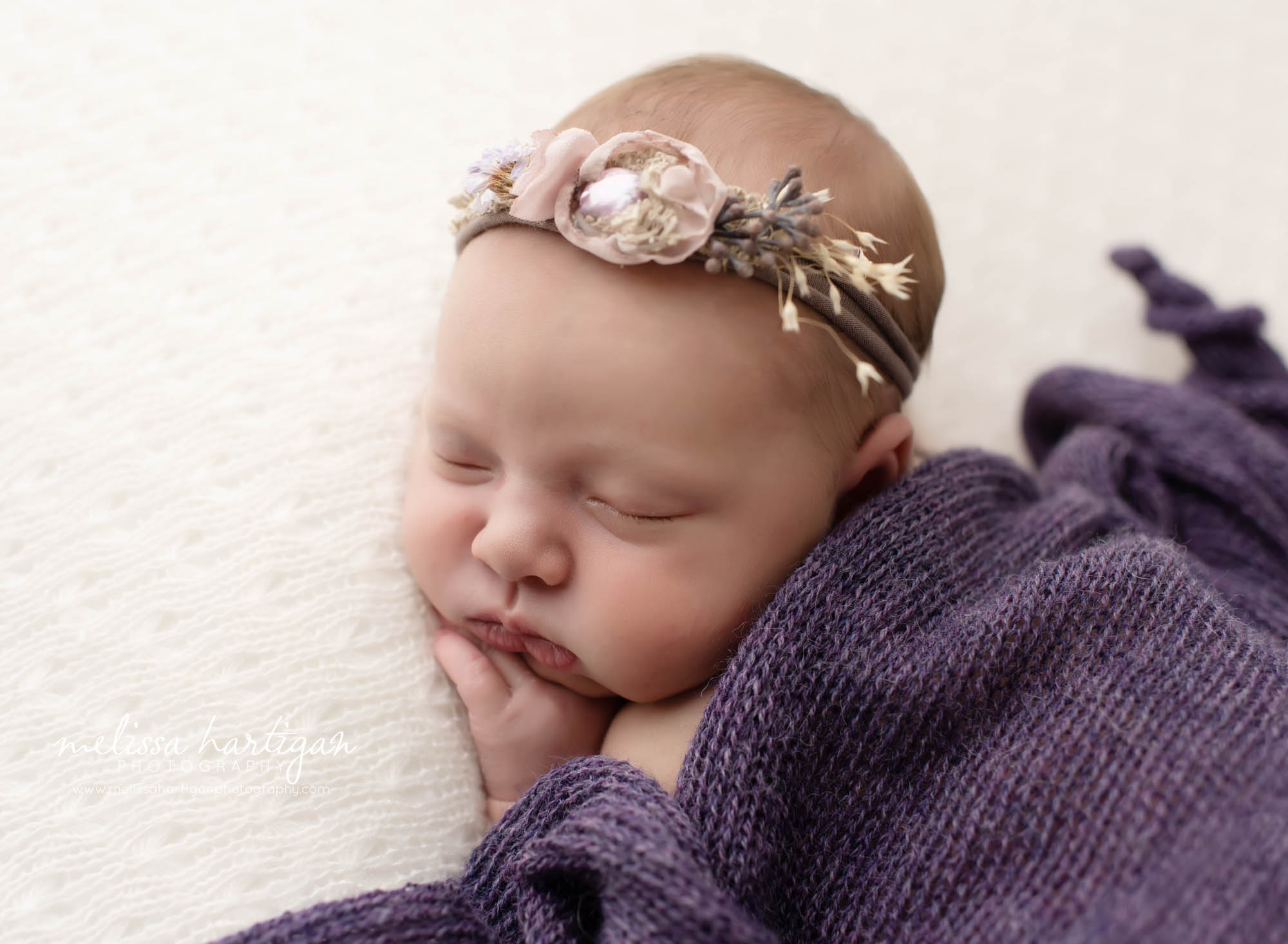 Baby girl posed on tummy with purple knitted wrap and floral headband newborn photography CT
