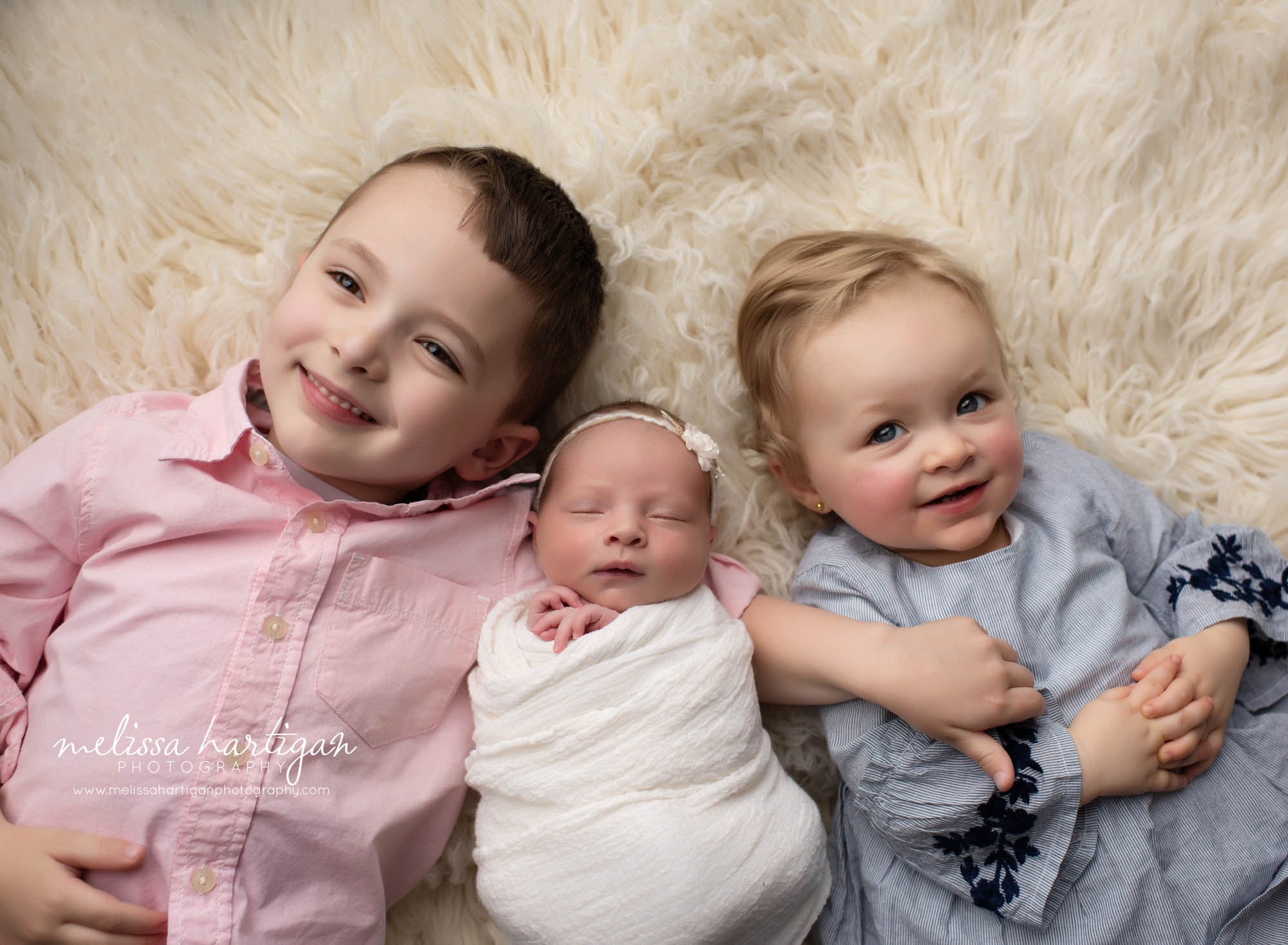 sibling photo pose laying down with baby and two older siblings