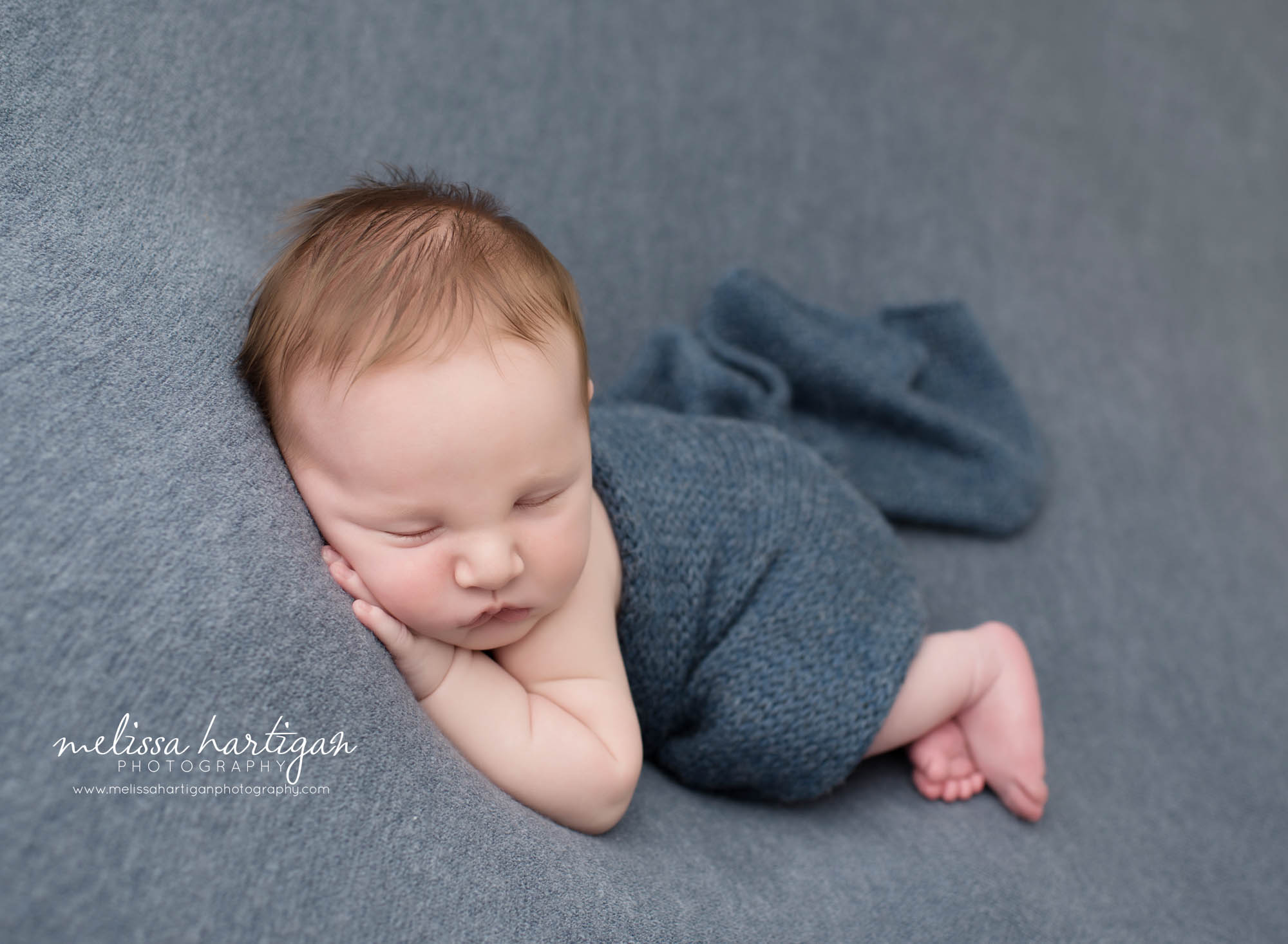 baby boy posed on wide with blue knitted wrap around him