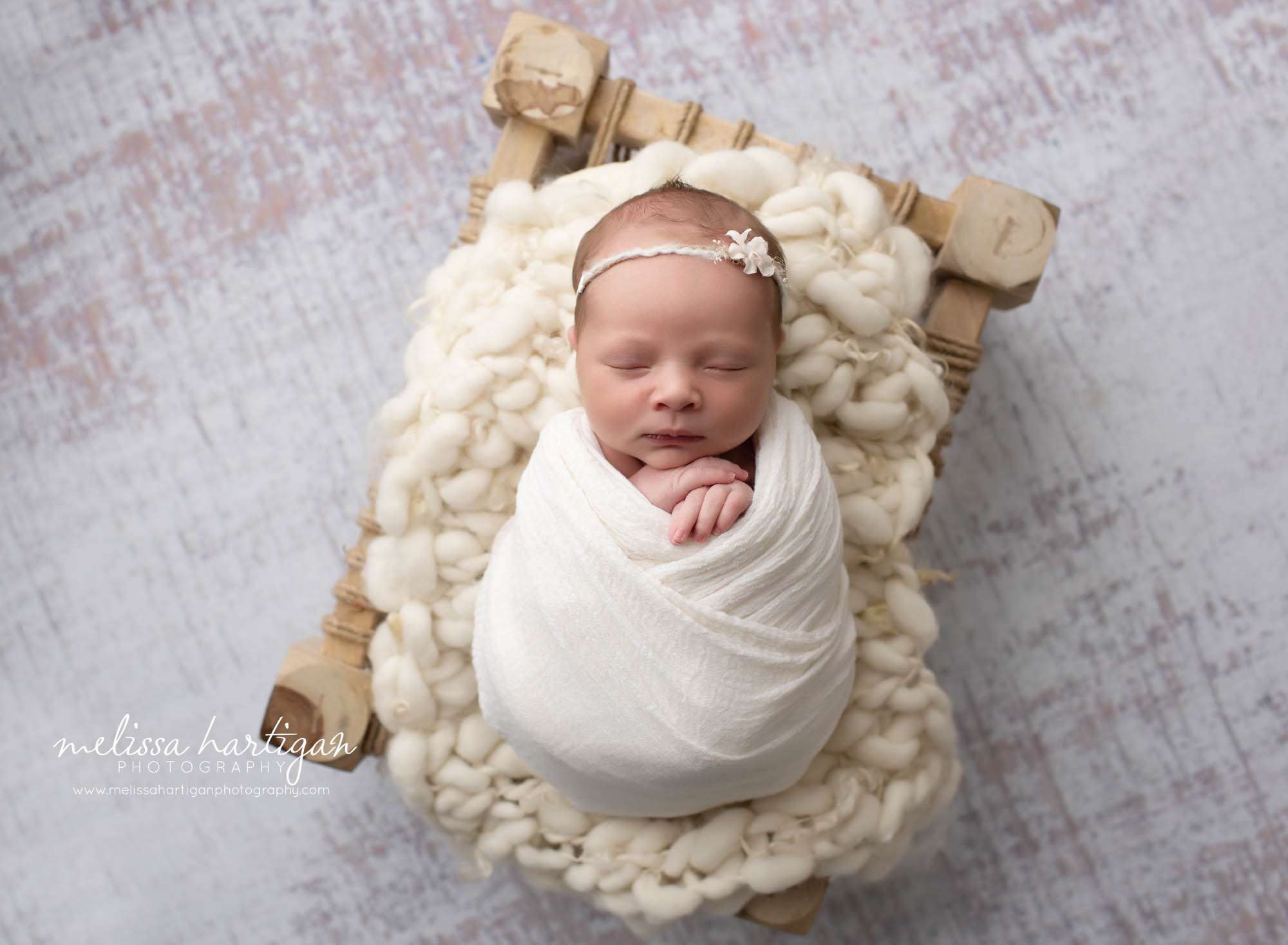 Baby girl wrapped on wooden prop with cream knitted layer