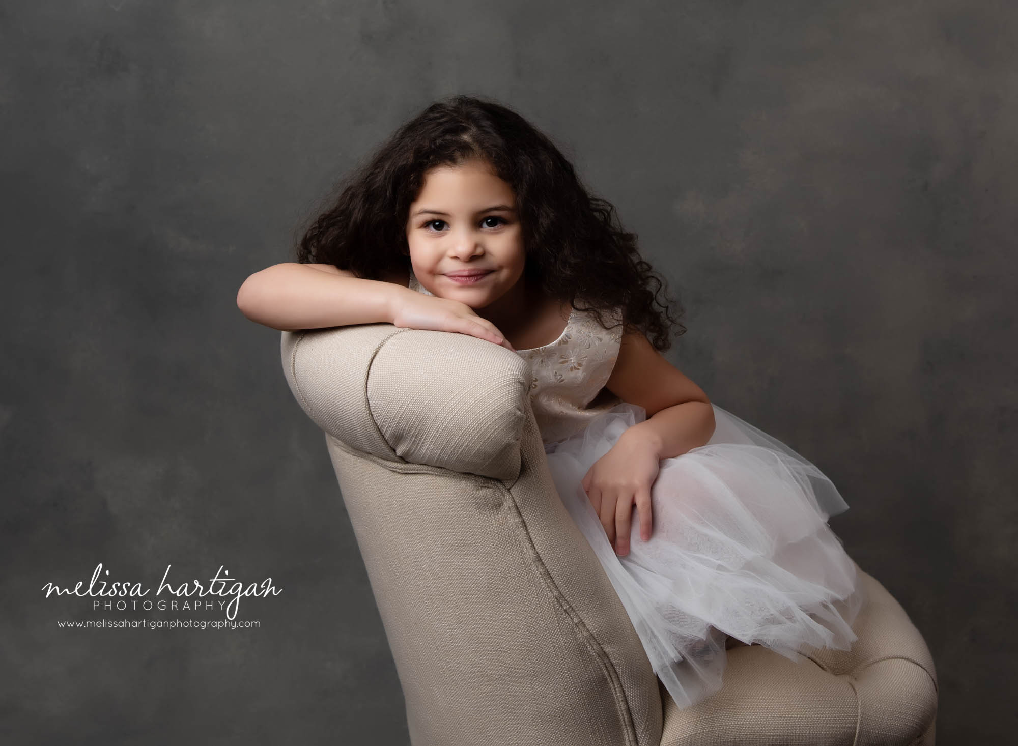 big sister sitting in chair for maternity session portrait