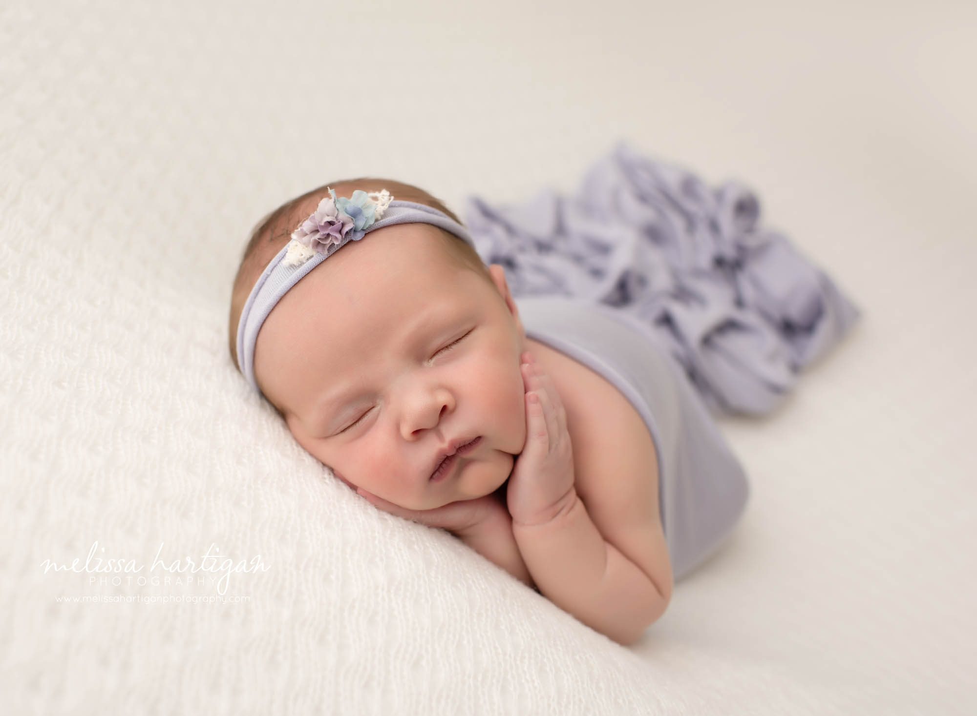 baby girl posed on side with light purple wrap and headband