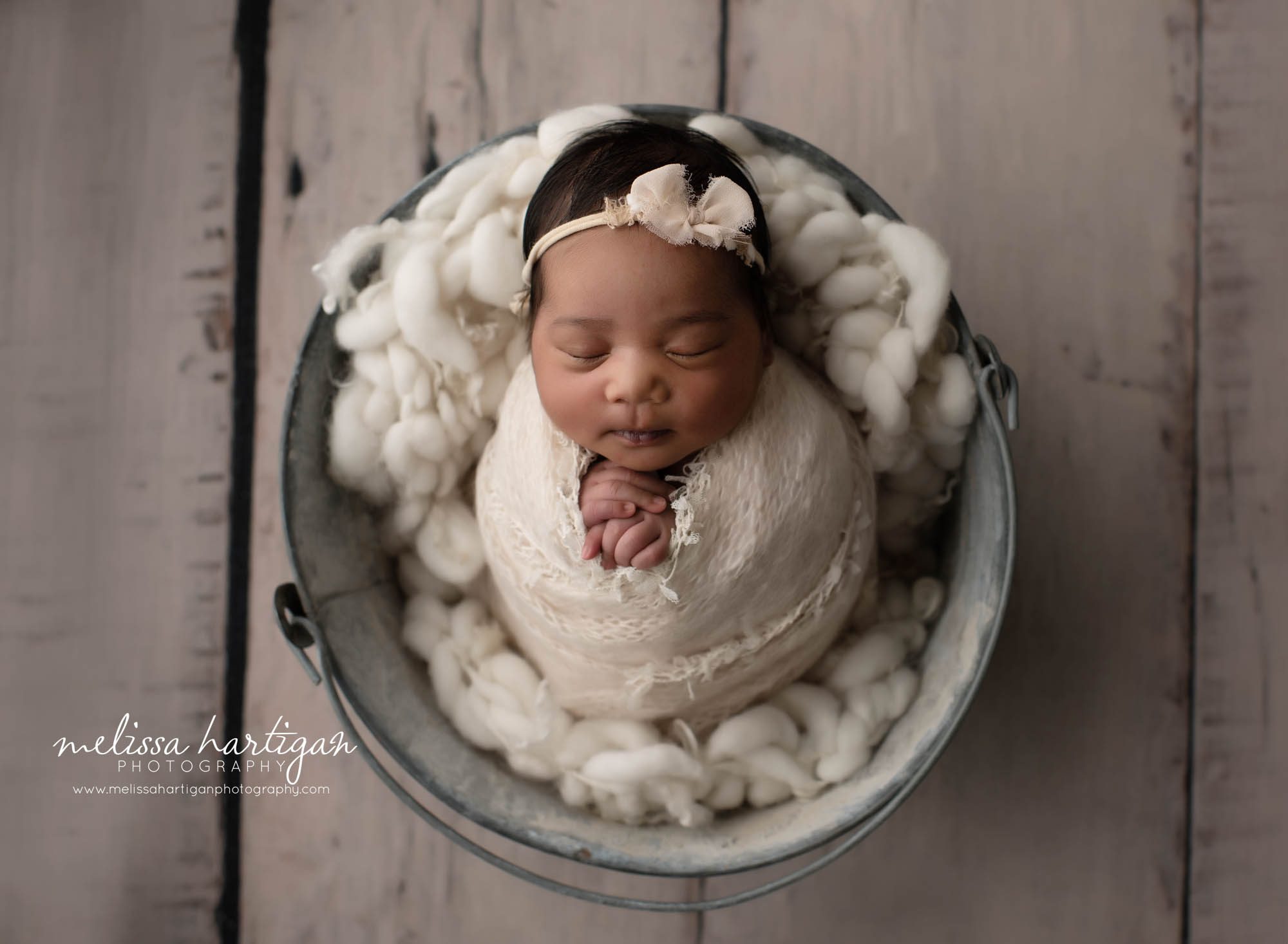 baby girl wrapped posed in bucket in cream colors and knitted layers