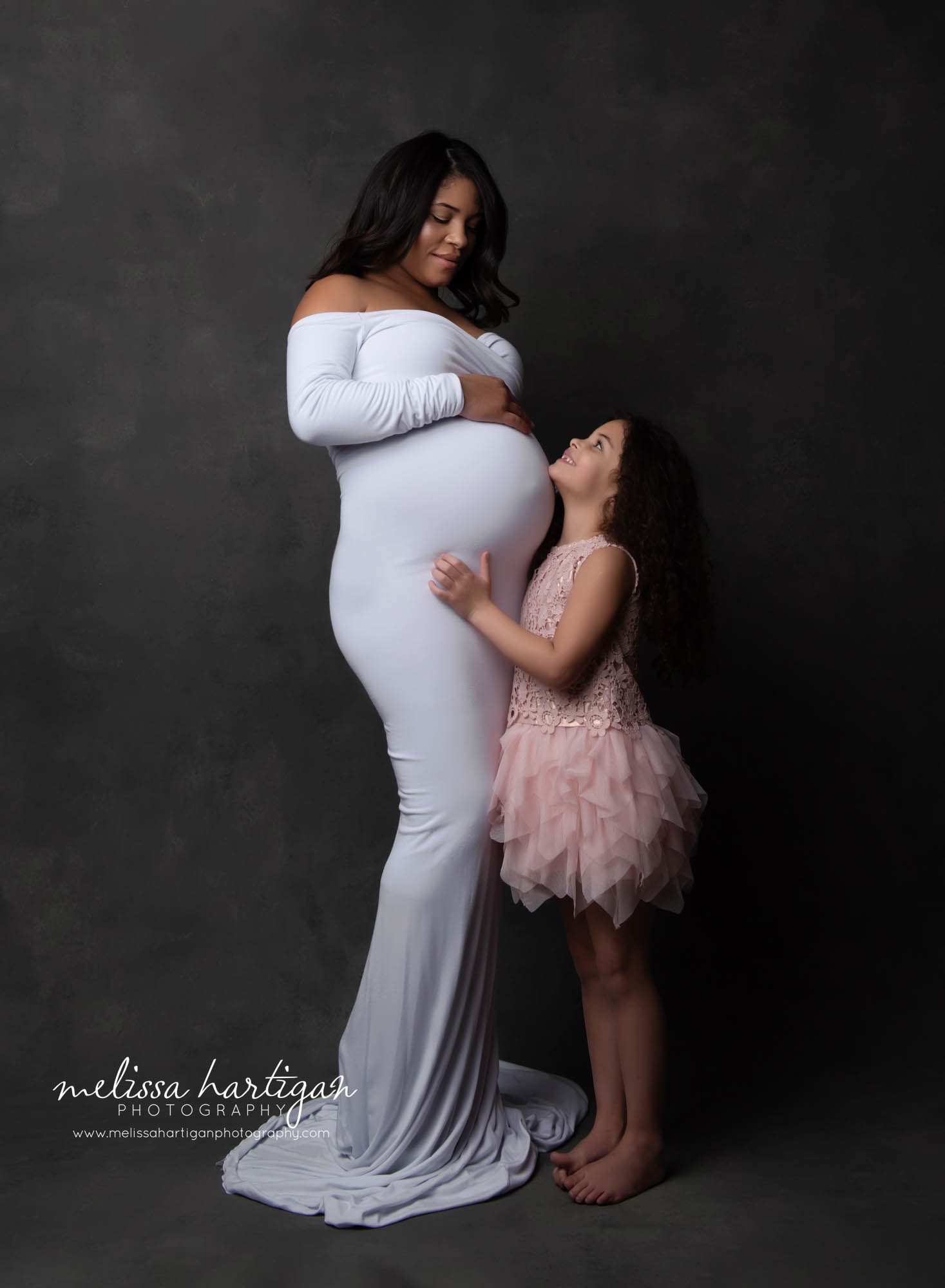 daughter looking up at mom with chin resting on moms baby bump studio photoshoot Waterbury CT Maternity Photographer