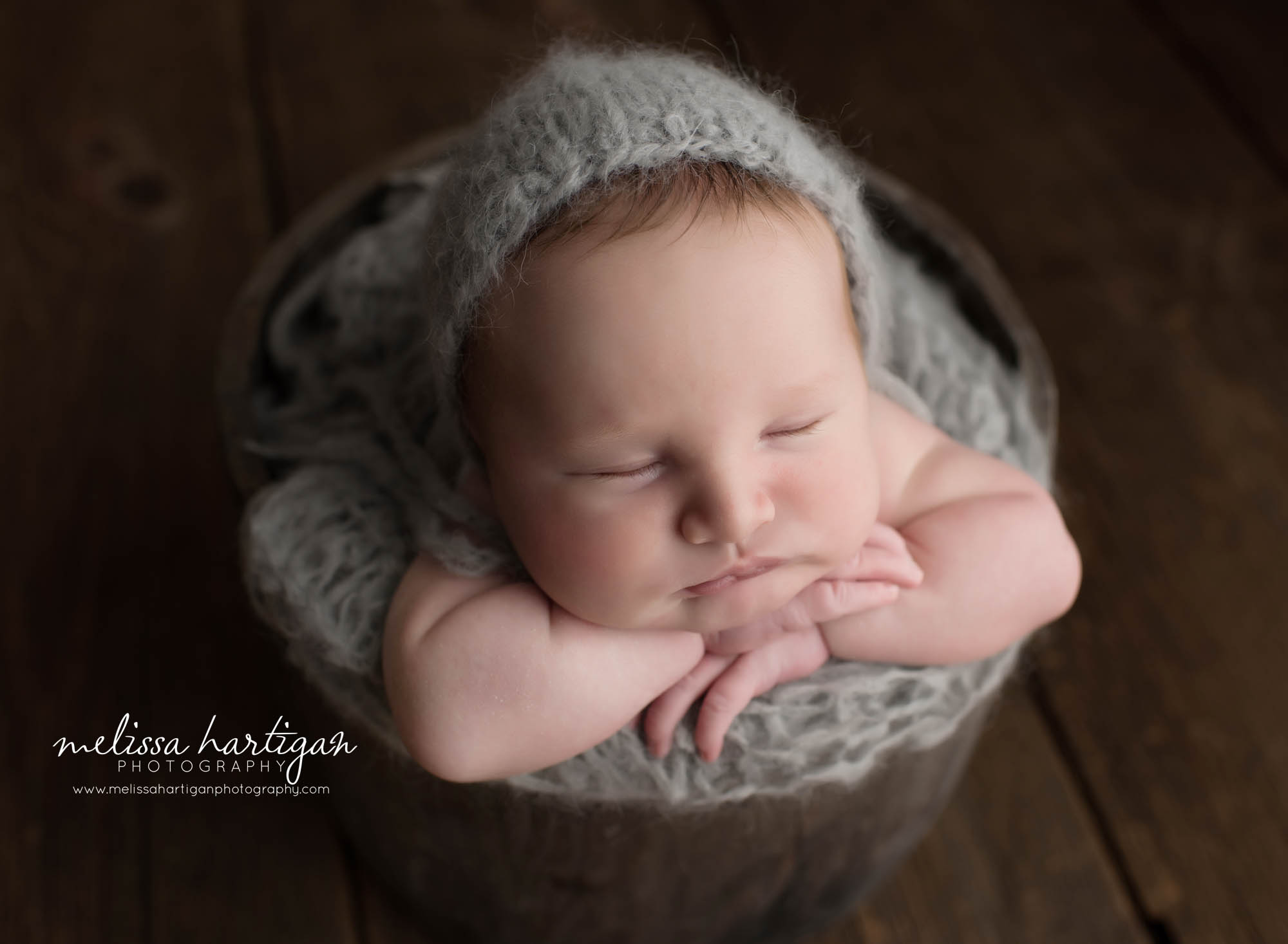 baby boy posed in wooden bucket with gray knitted bonnet