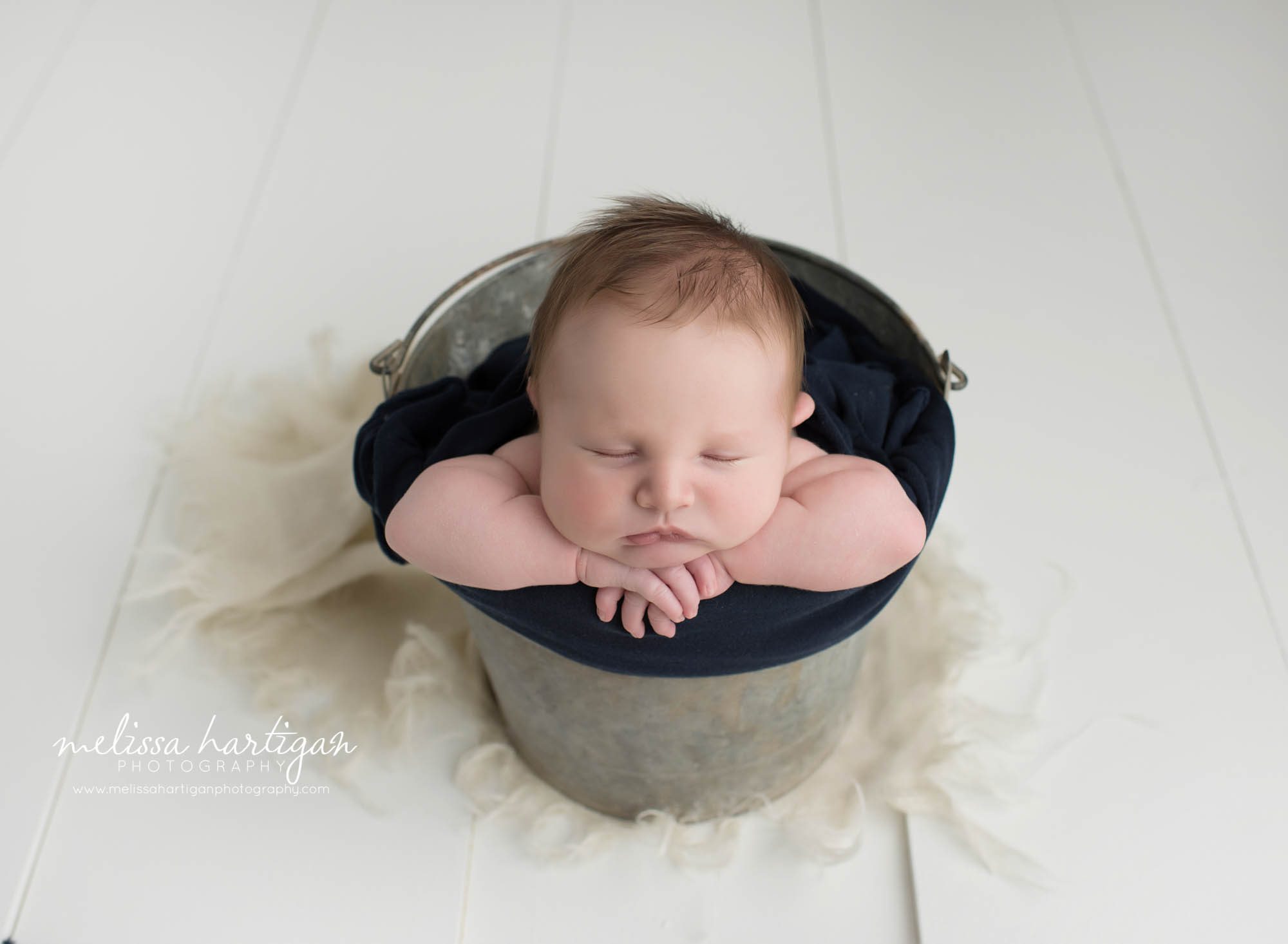 baby boy posed in metal bucket with navy blue colors