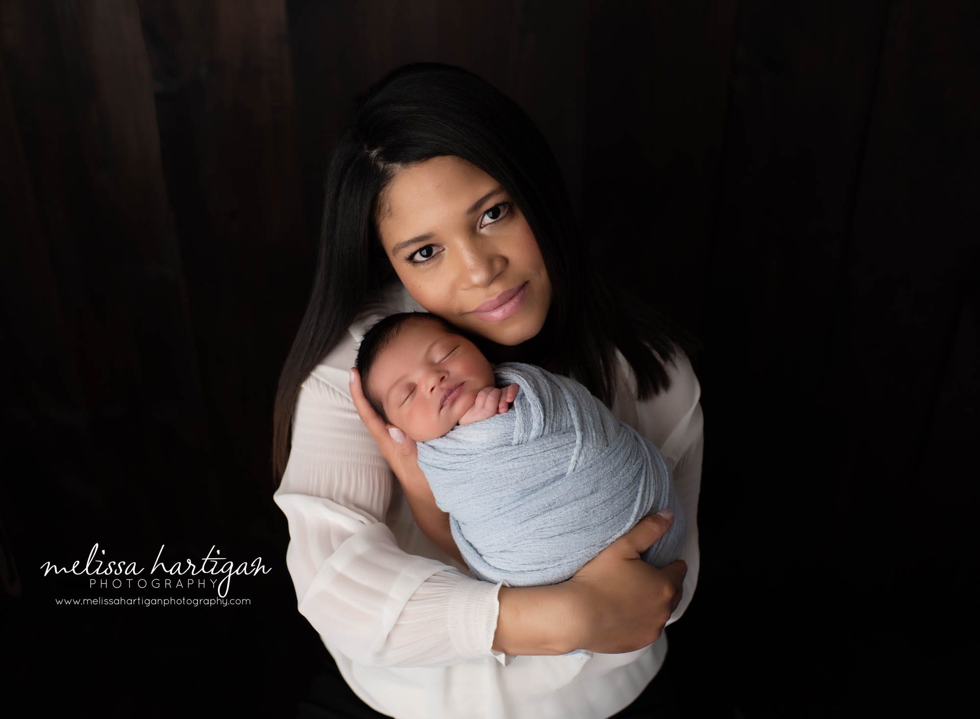 mom holding her newborn baby boy in studio newborn photography session parents pose