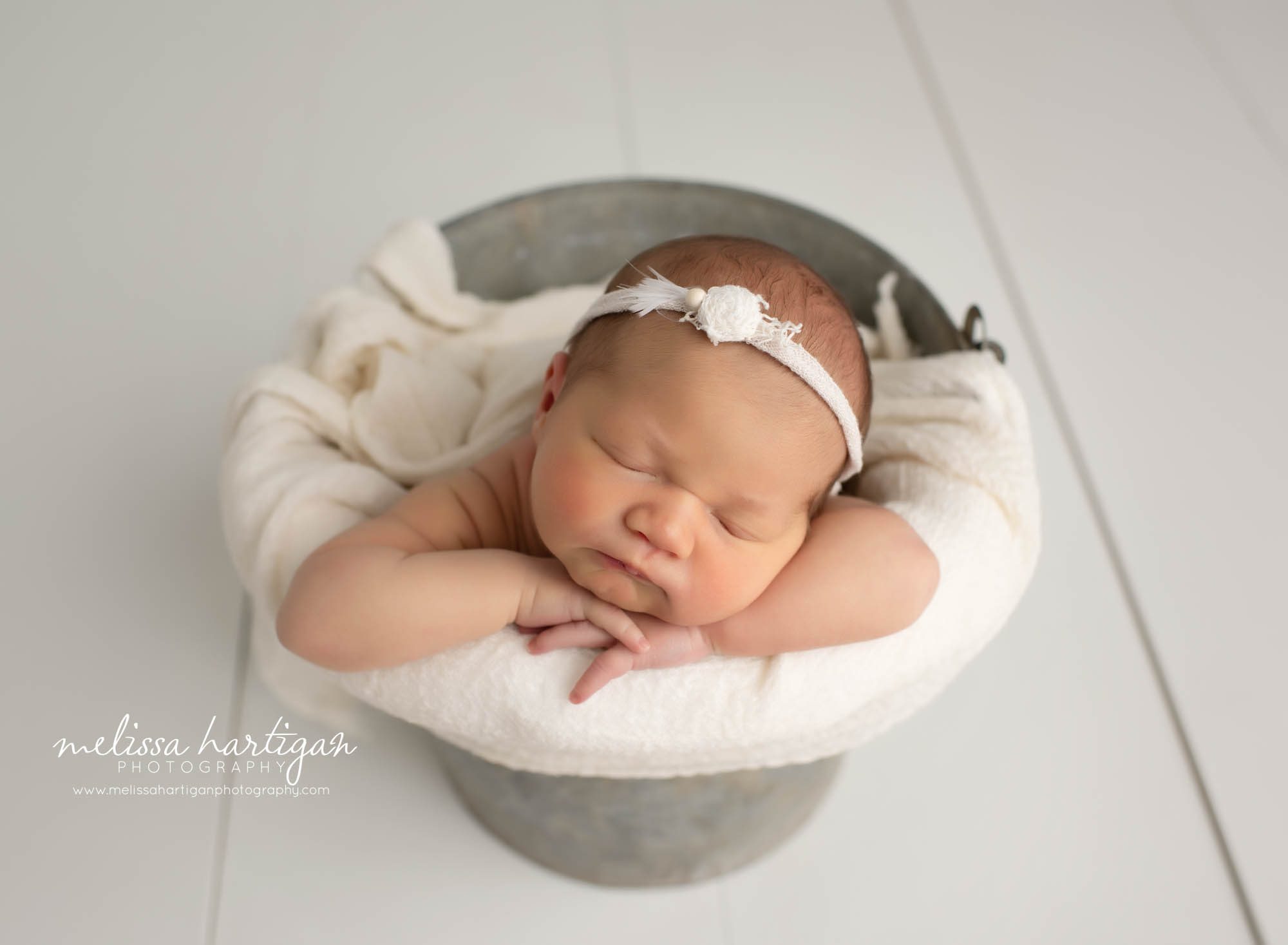 Newborn baby girl posed in metal bucket with cream colored wrap and headband CT newborn Photography
