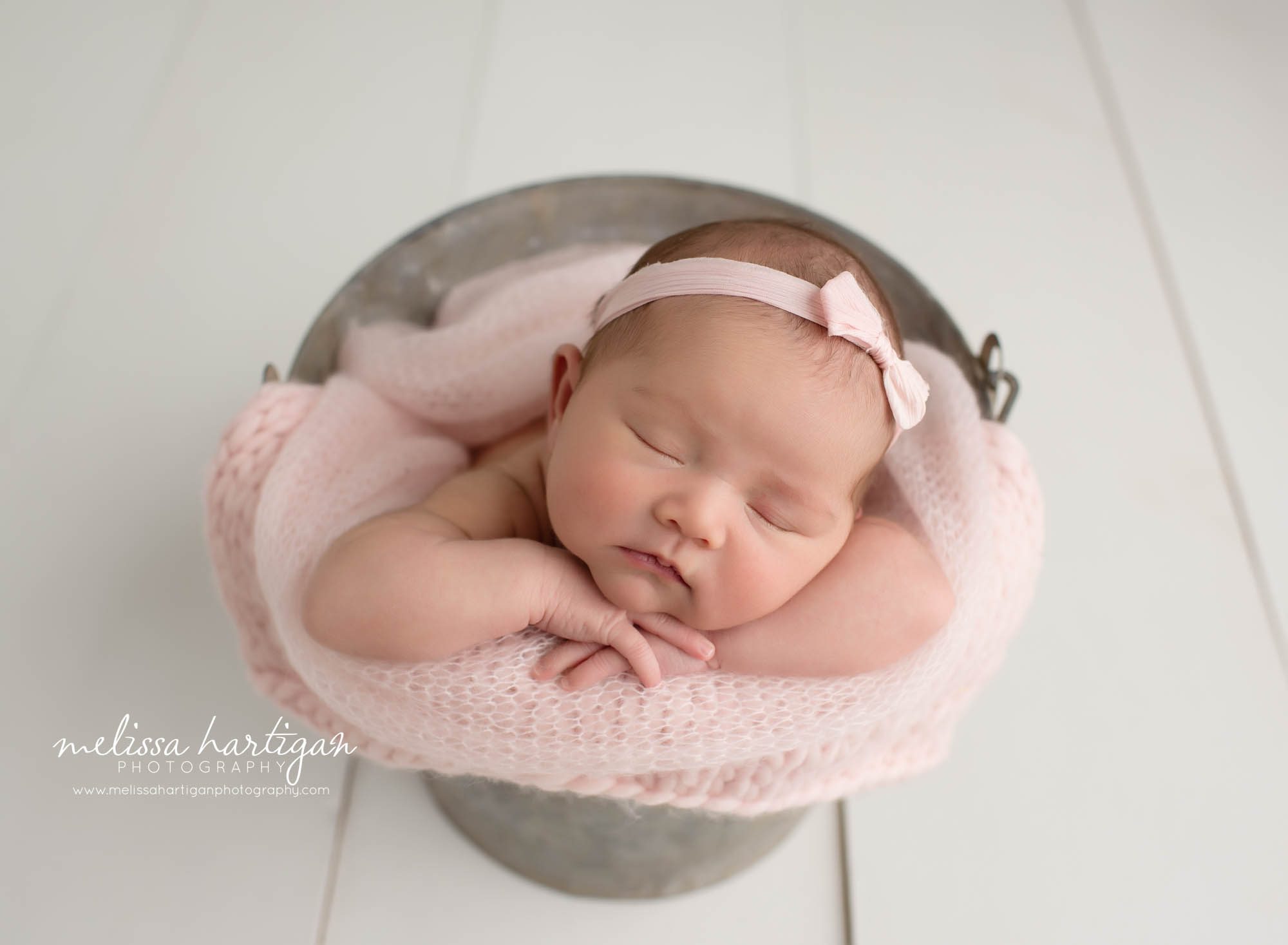 baby girl posed in metal bucket with pink knitted layer wrap