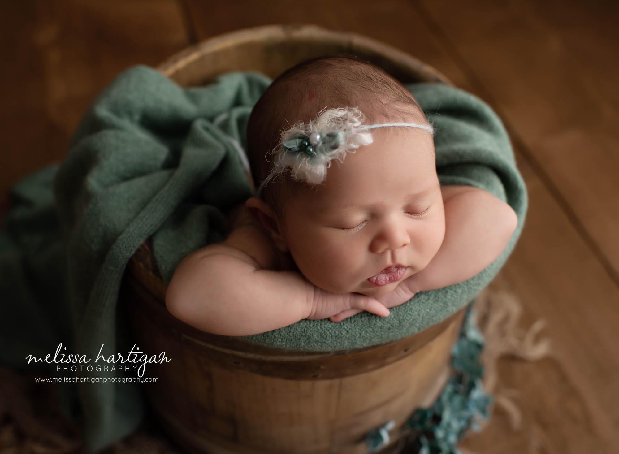 baby girl posed with chin on hands in rustic wooden bucket with shades of green colors