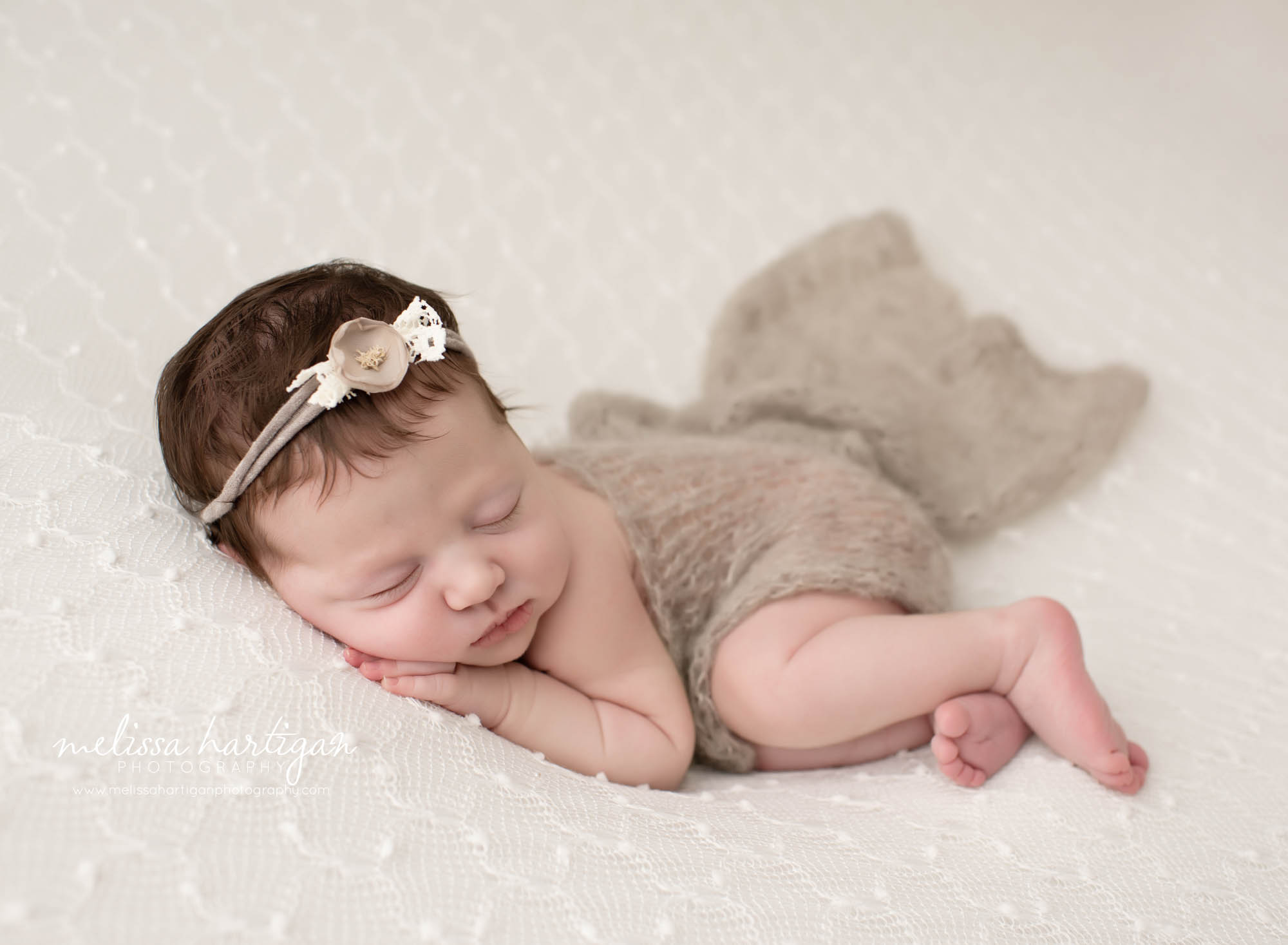 Baby girl posed on side with hand under chin and flower headband