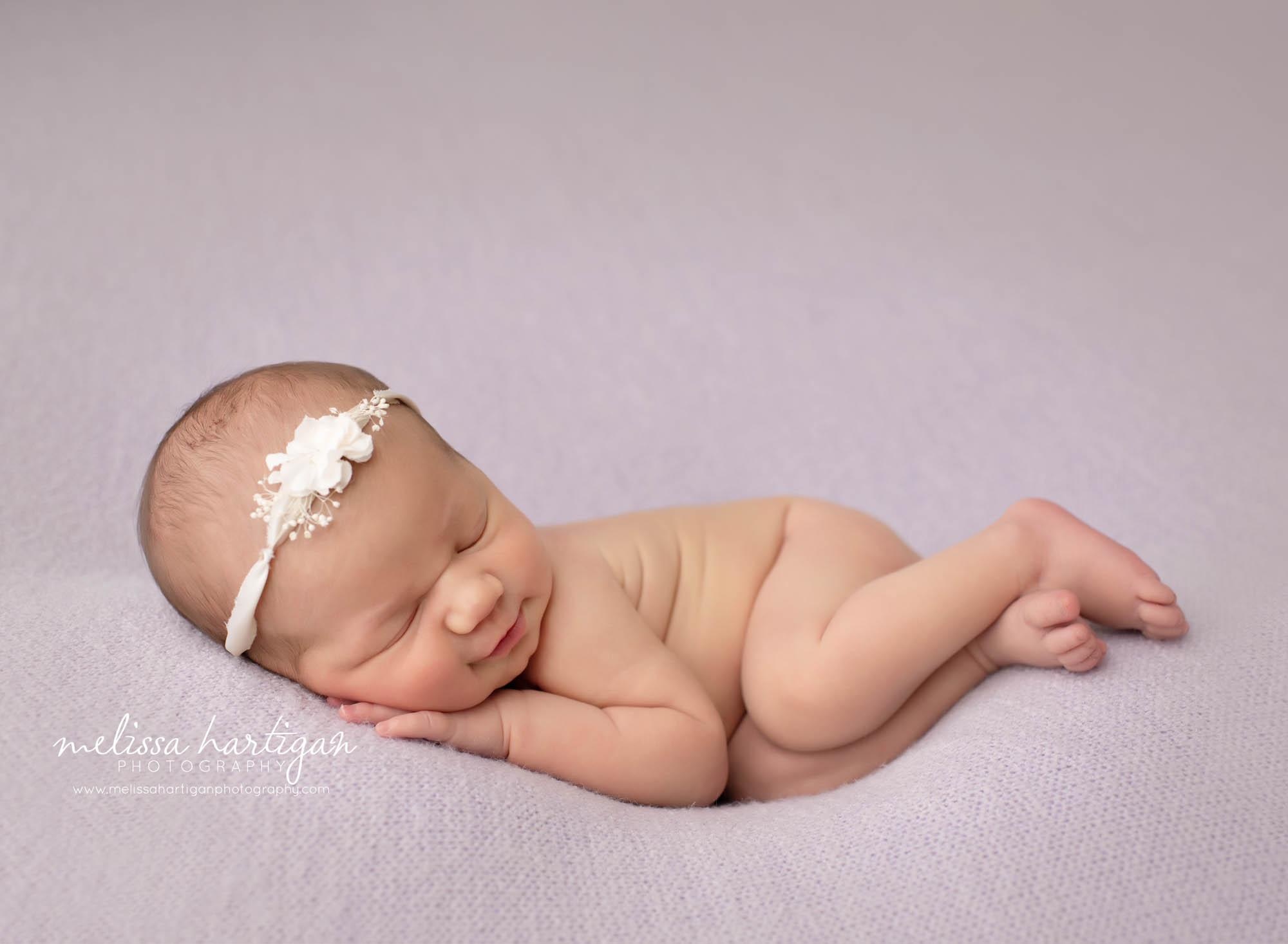 baby girl posed on light purple backdrop with flower tieback CT newborn photographer