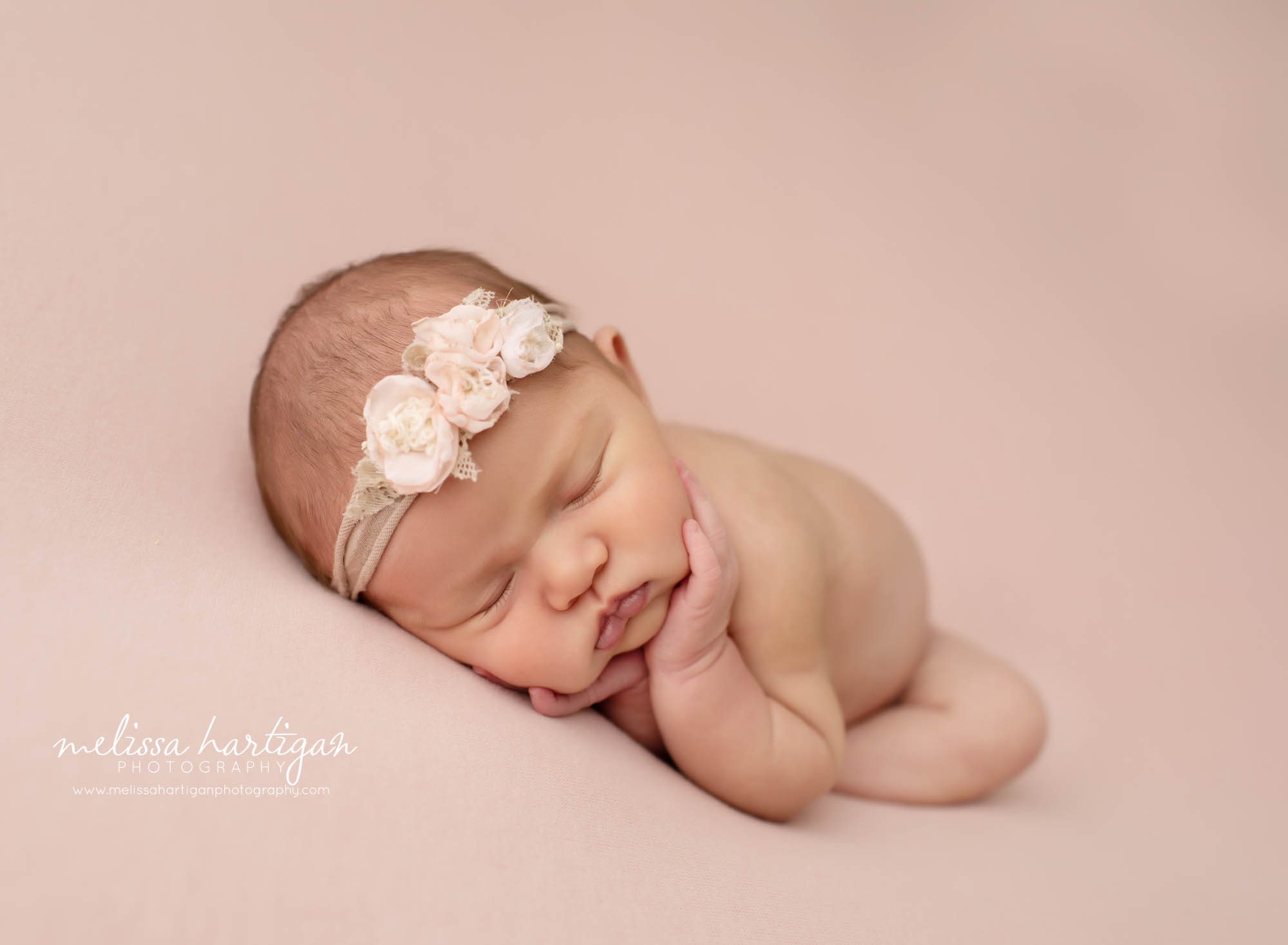 baby girl posed on side with hands under chin with pink floral headband