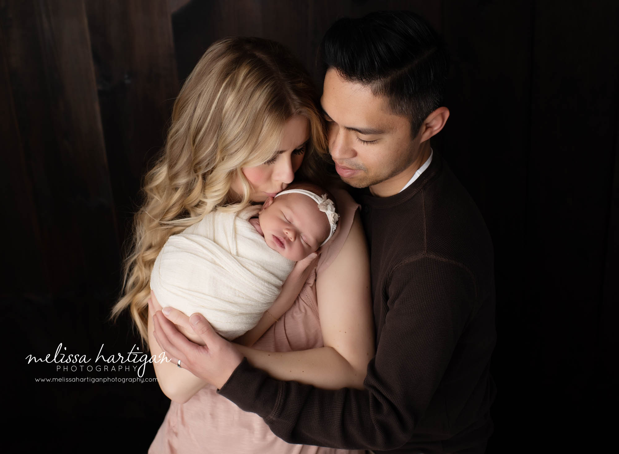 mom dad and baby girl newborn session family photo mom kissing baby