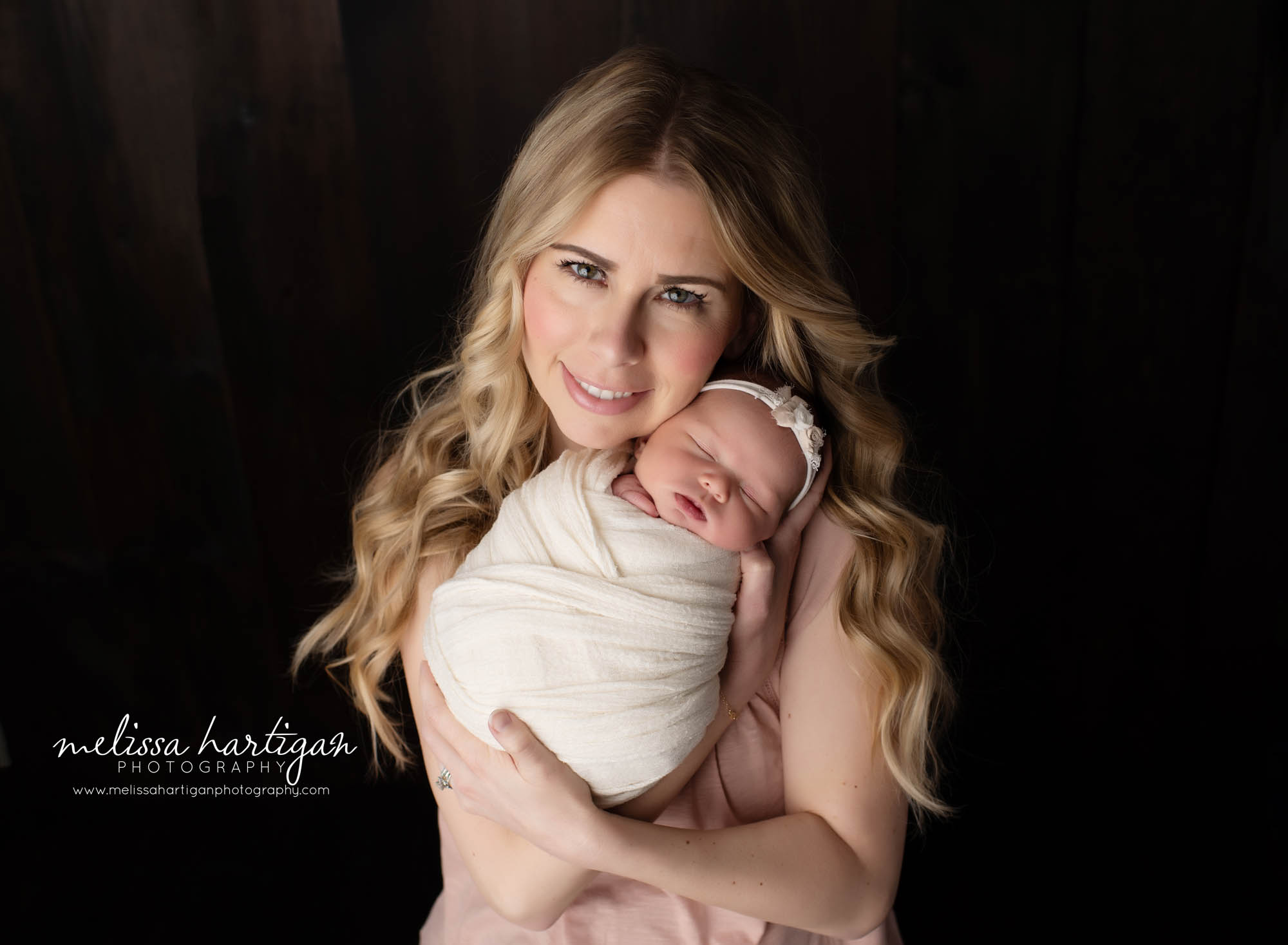 mom smiling holding newborn baby girl in studio baby sesison