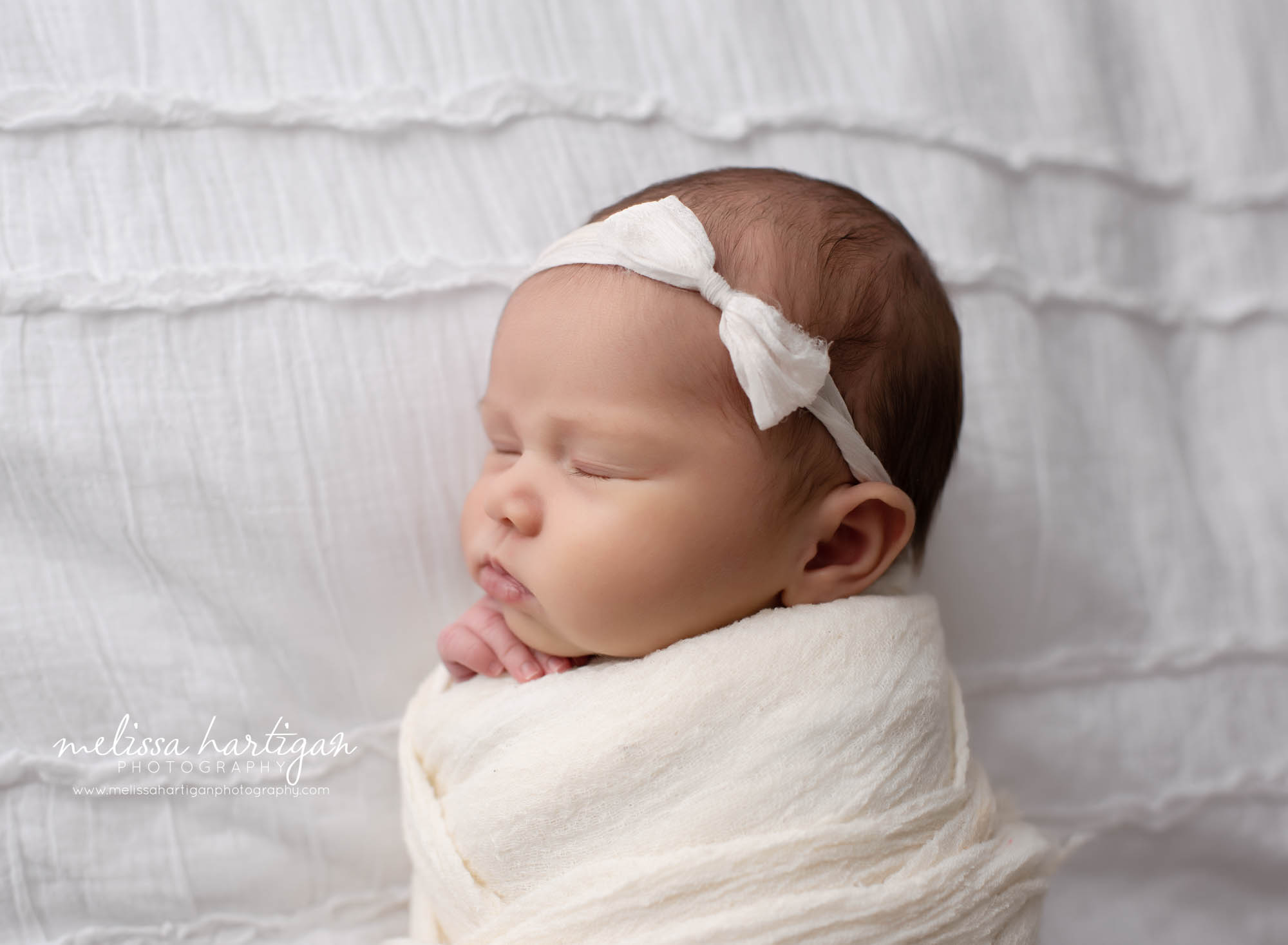 baby girl side profile wrapped on bed wearing cream bow headband