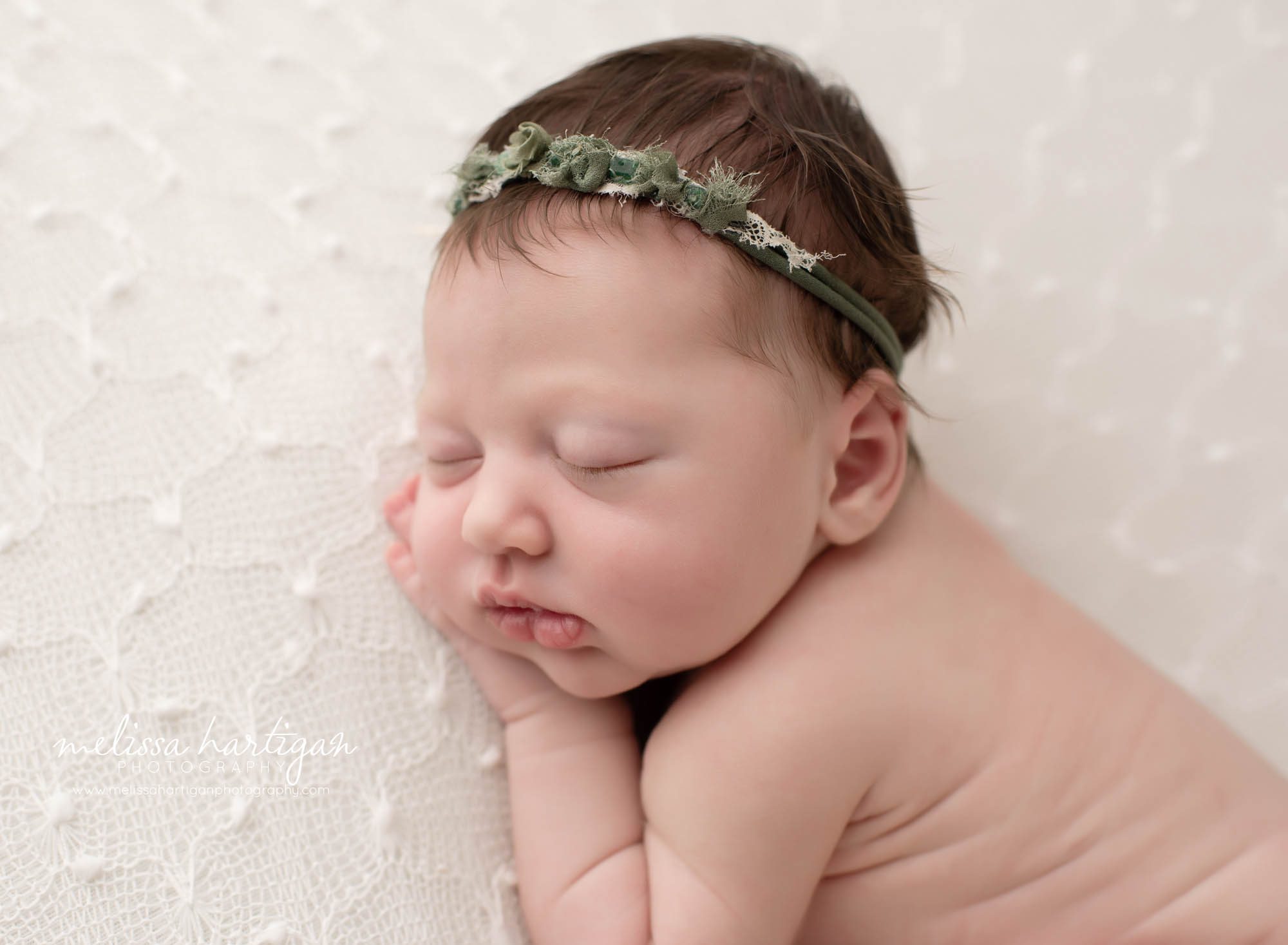 baby girl posed on side with hand under cheek and green headband