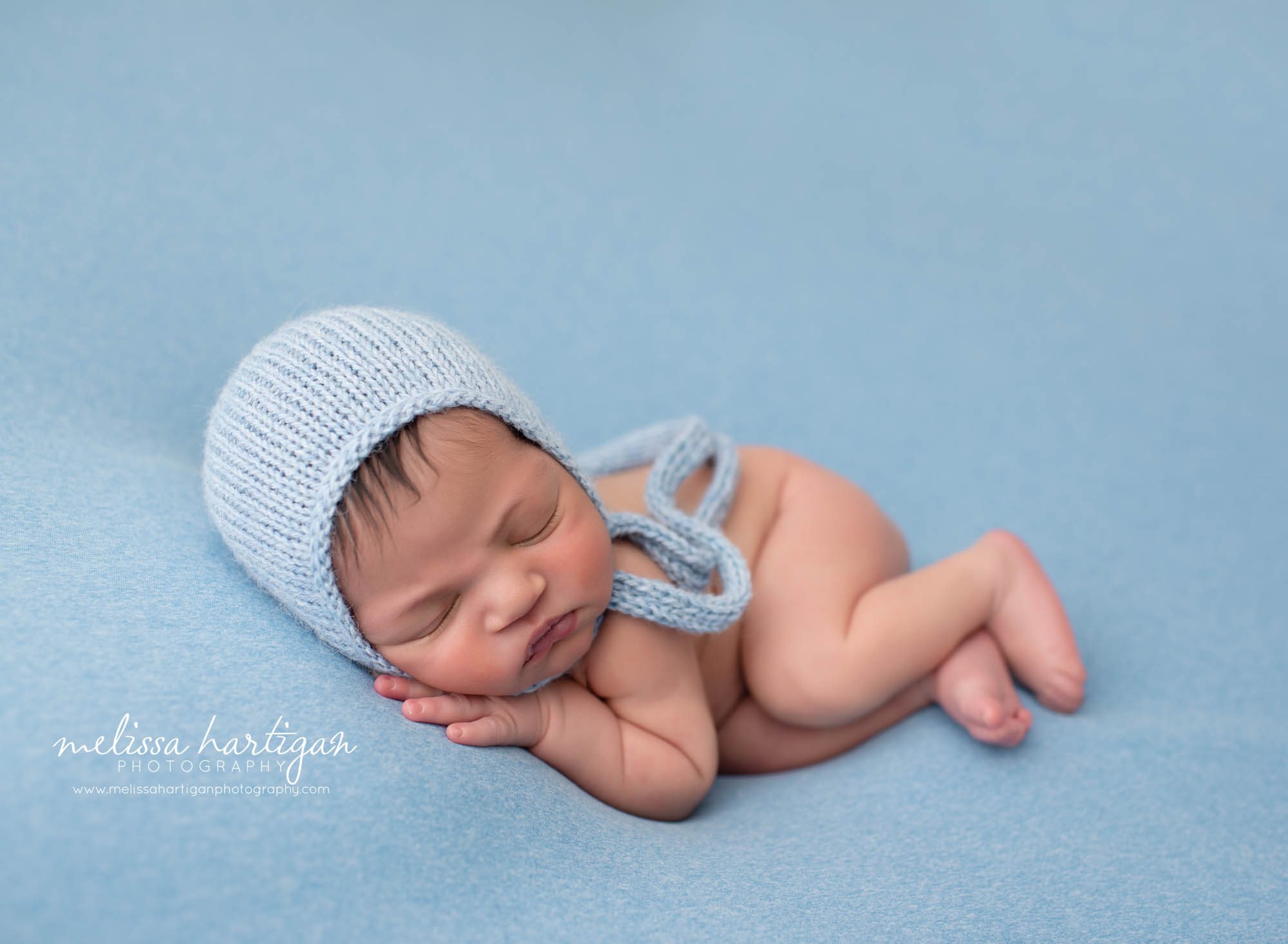 baby boy posed on side with blue knitted bonnet on Waterbury CT newborn photography