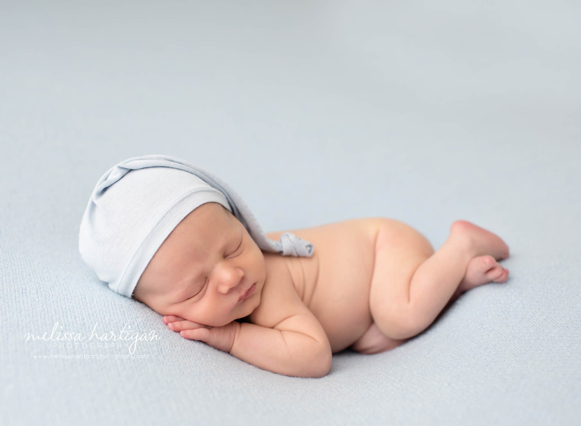 baby boy posed on lightblue backdrop wearing light blue sleepy cap CT Newborn Photographer CT