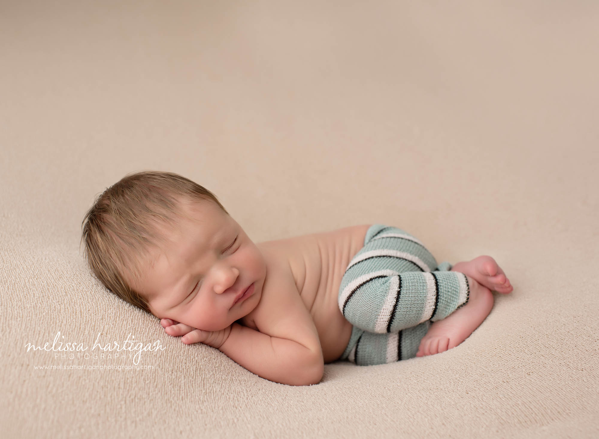 baby boy posed on side with newborn pants on