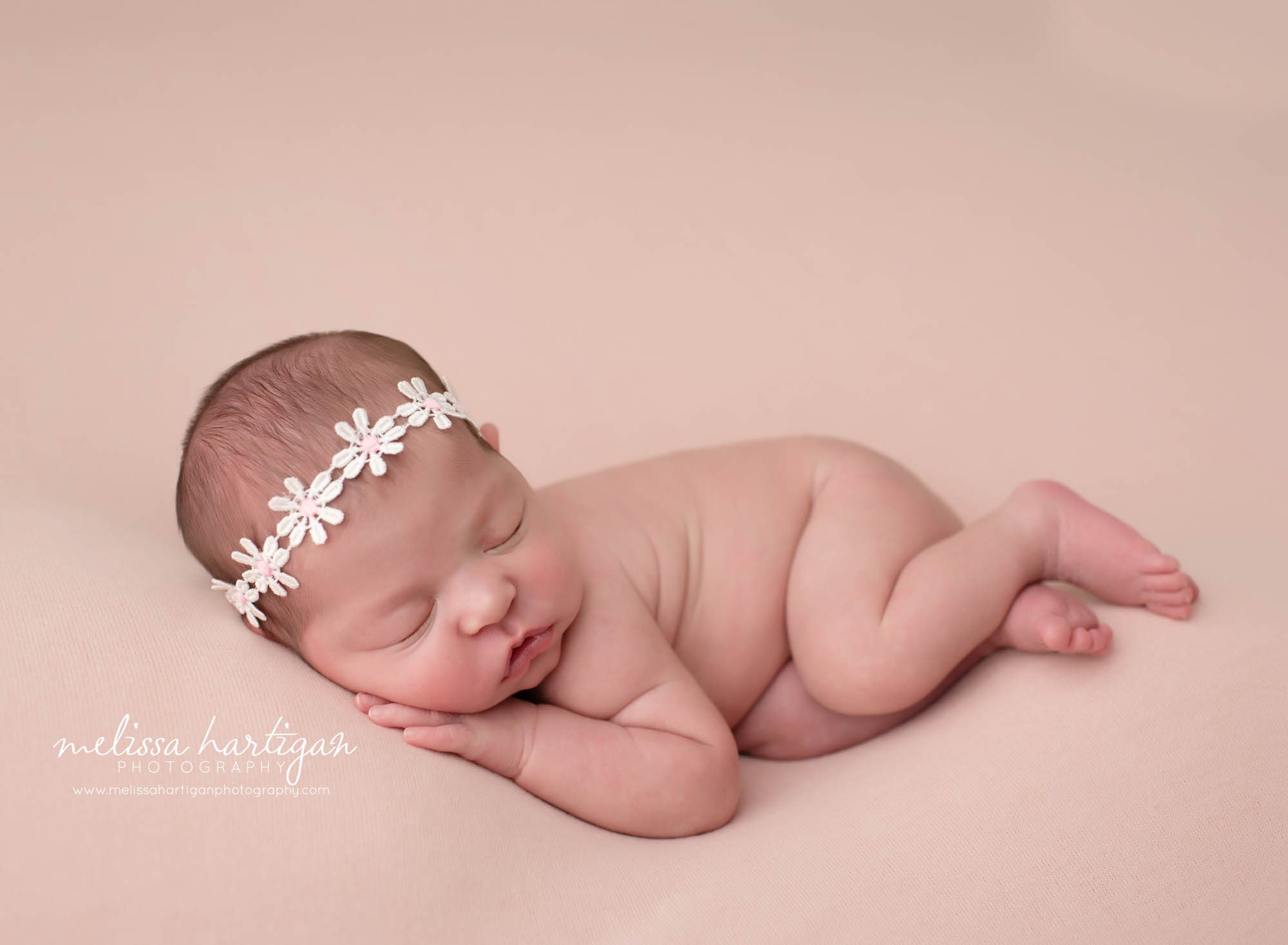 Baby girl posed on side with white flower headband
