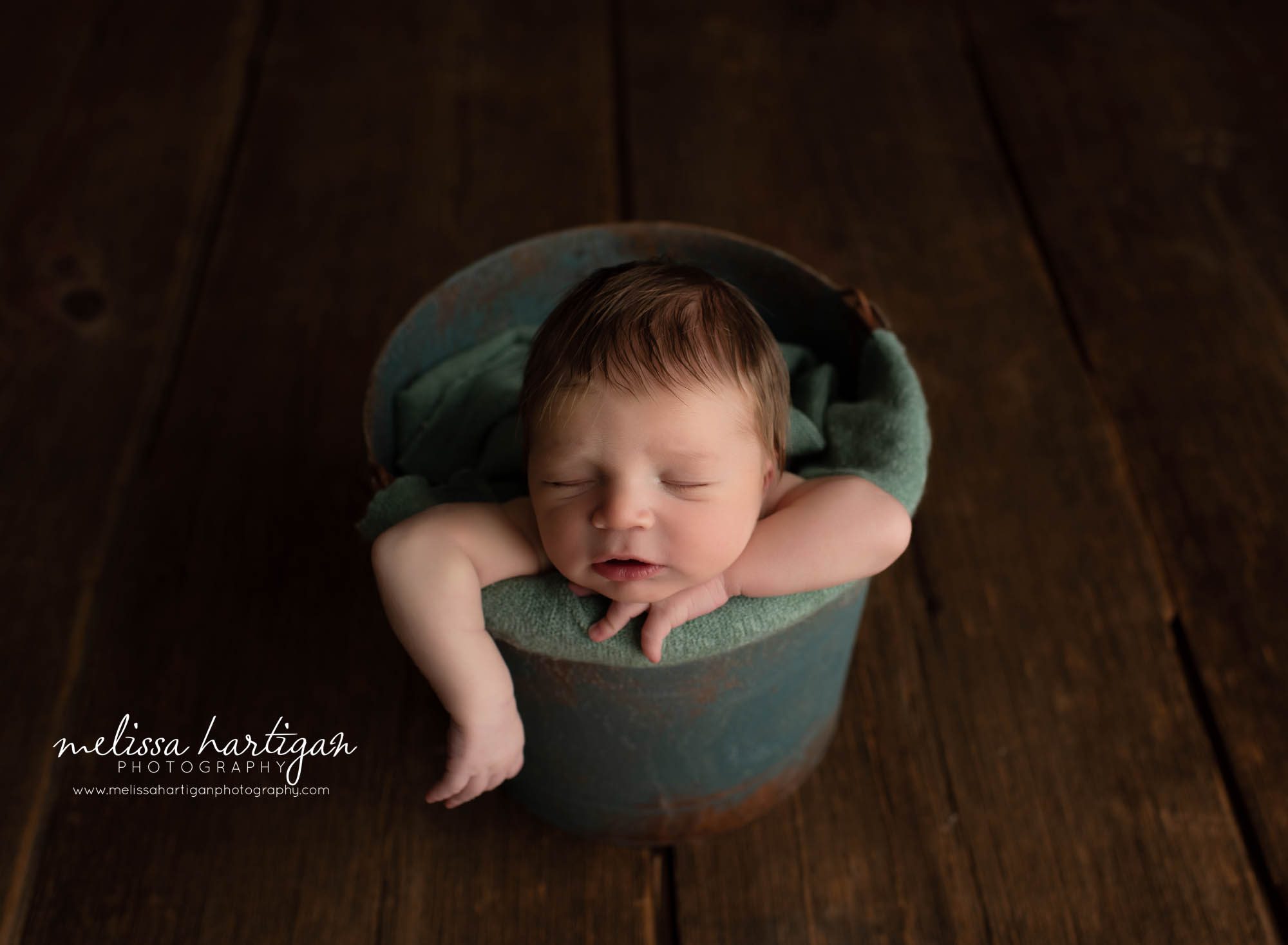 baby boy posed in bucket with arm hanging out