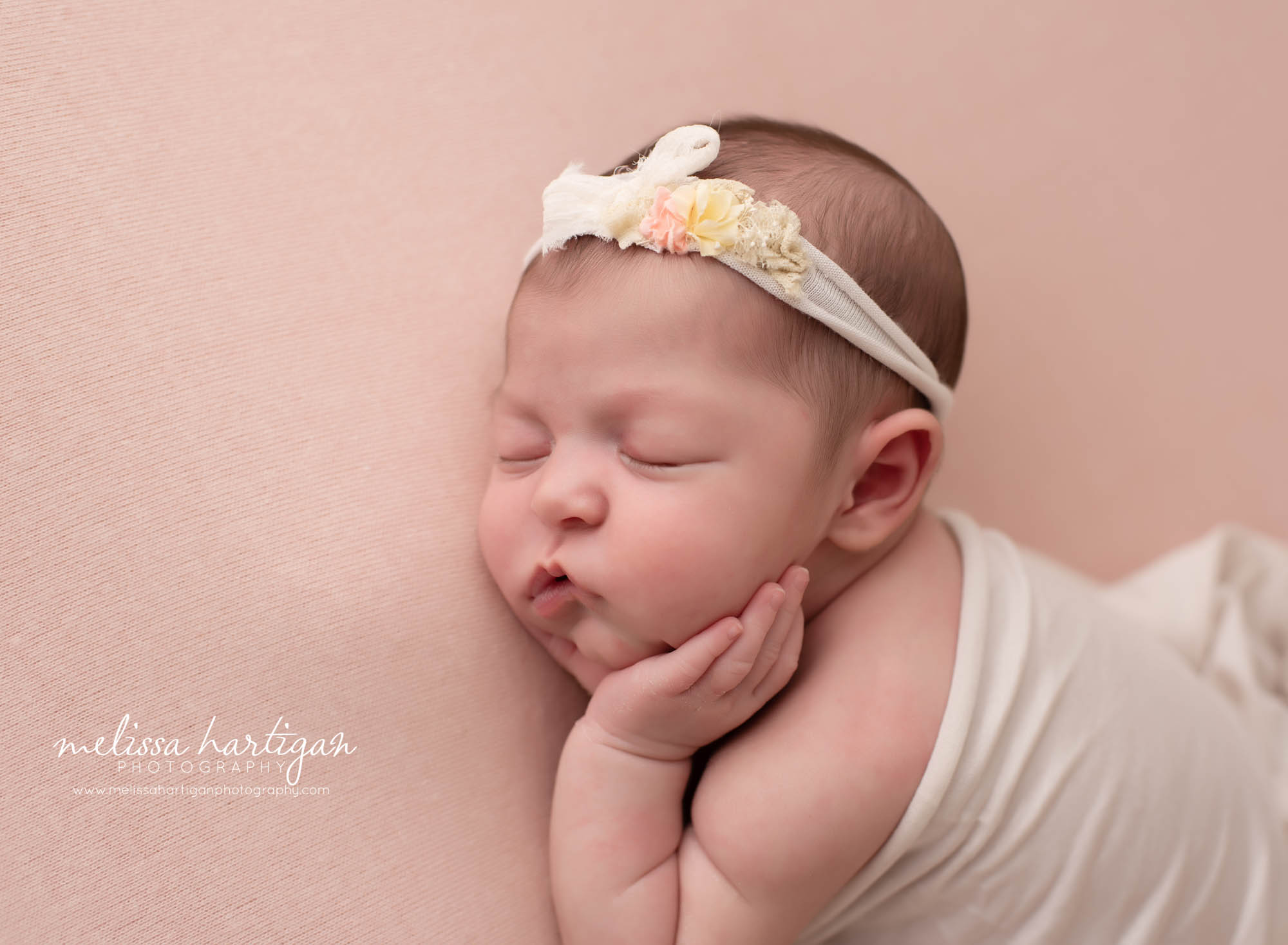 baby girl posed on side with hands on cheeks