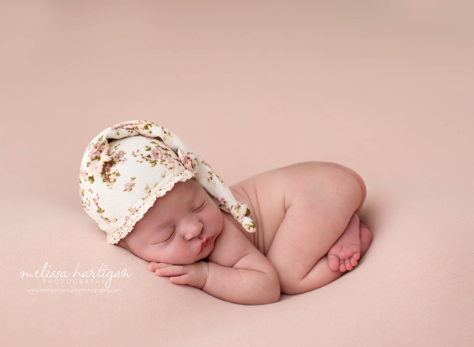 baby girl posed on pink blanket with white sleepy cap and pink flowers CT newborn Photography