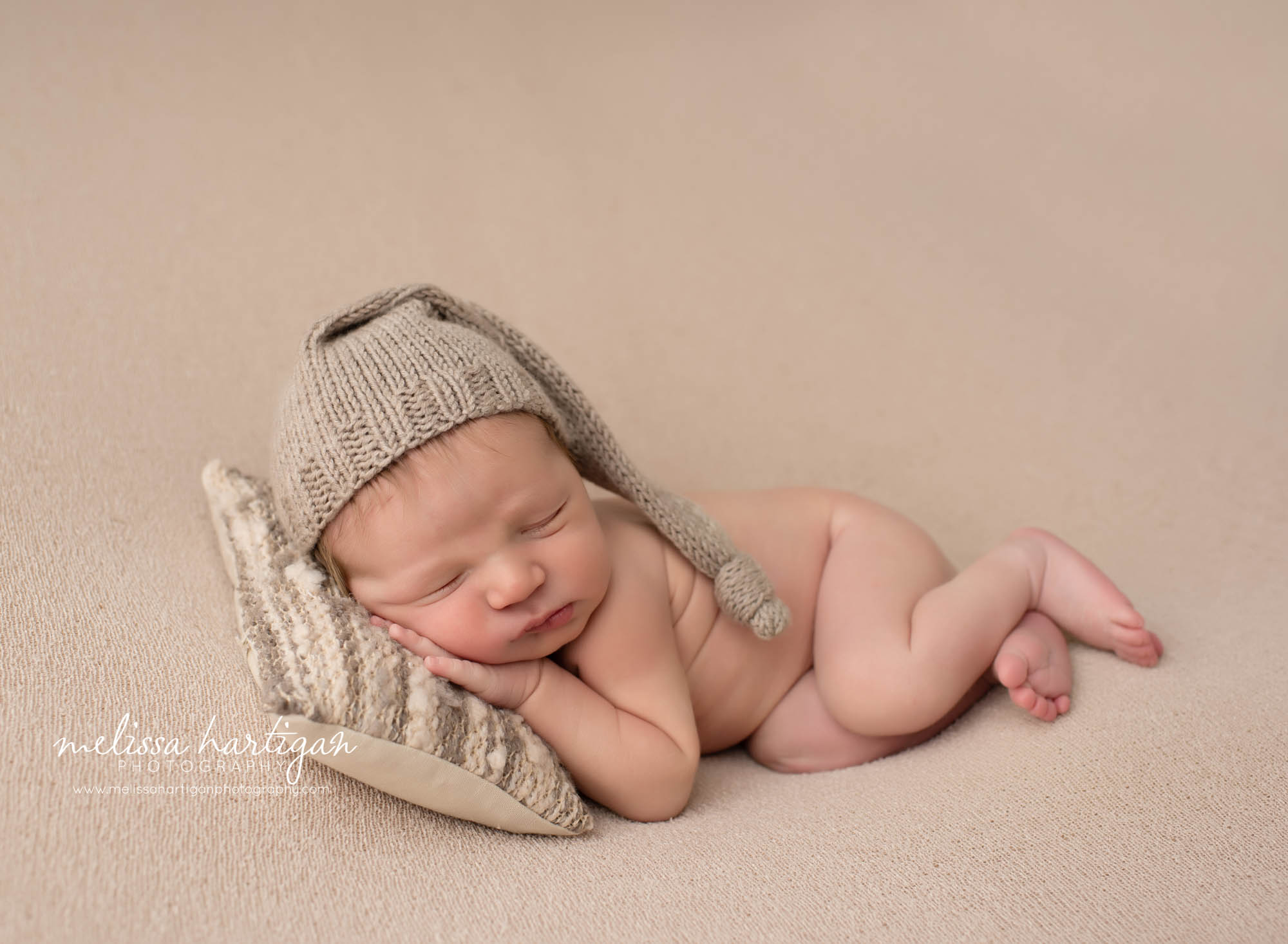 baby boy posed on side sleeping with head on newborn pillow