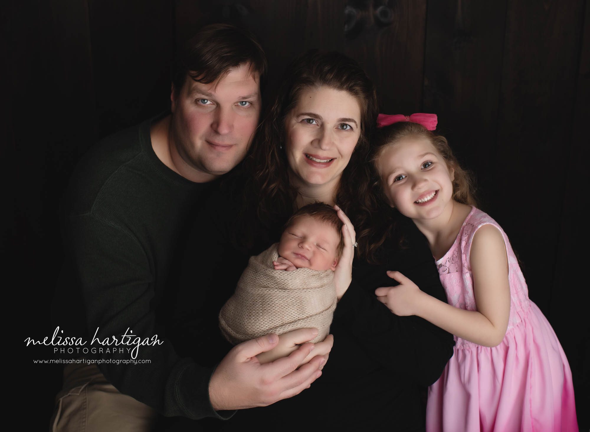 mom dad older sister and newborn baby boy family photo pose in studio