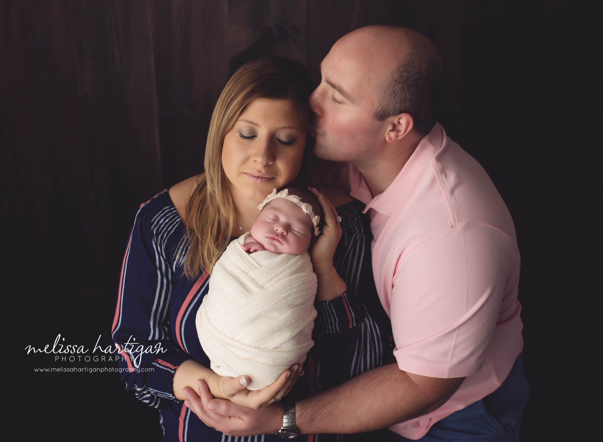 mom dad and newborn baby girl family pose in studio