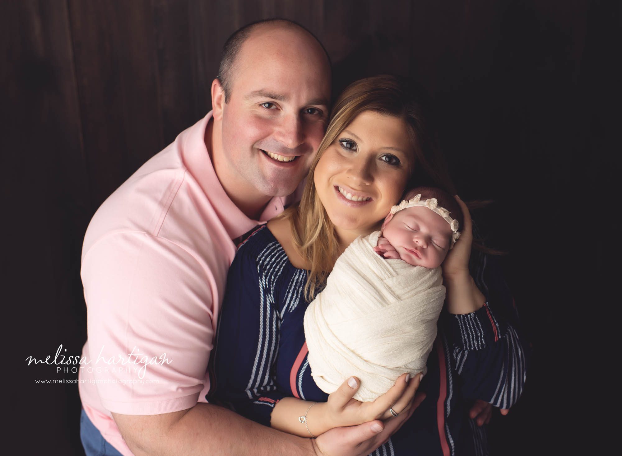 mom dad and wrapped newborn baby girl family pose in newborn photo session CT