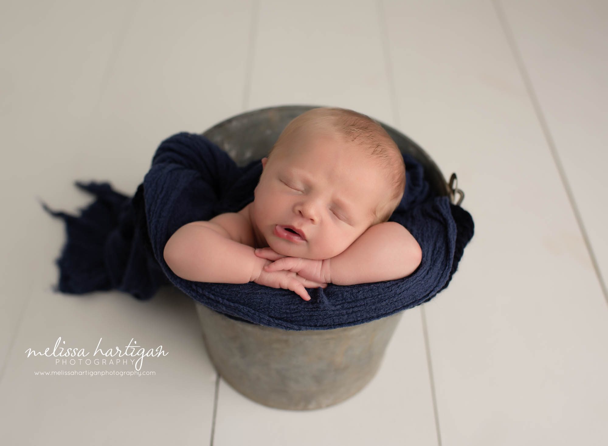 Baby boy posed in metal bucket with navy blue wrap