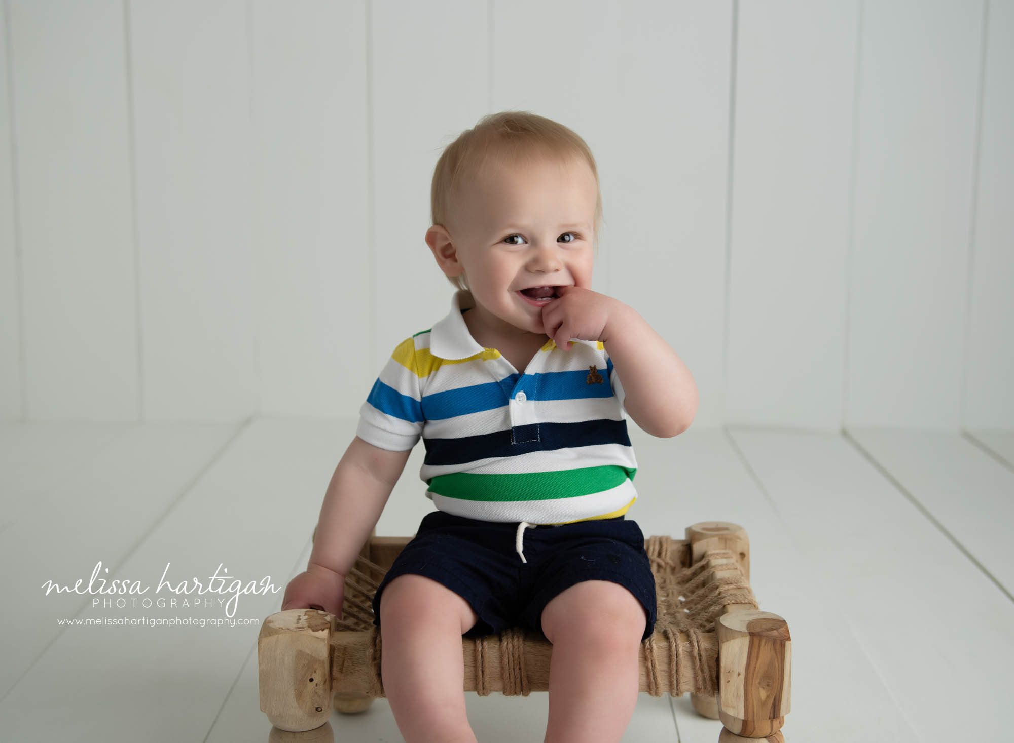 baby boy sitting on wooden prop in studio baby milestone session