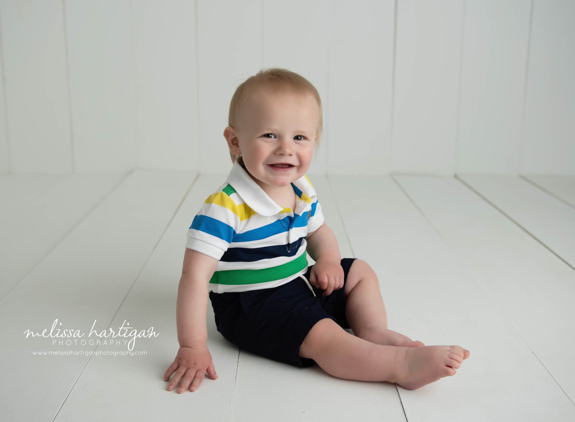 baby boy sitting on wooden boards in photography studio session