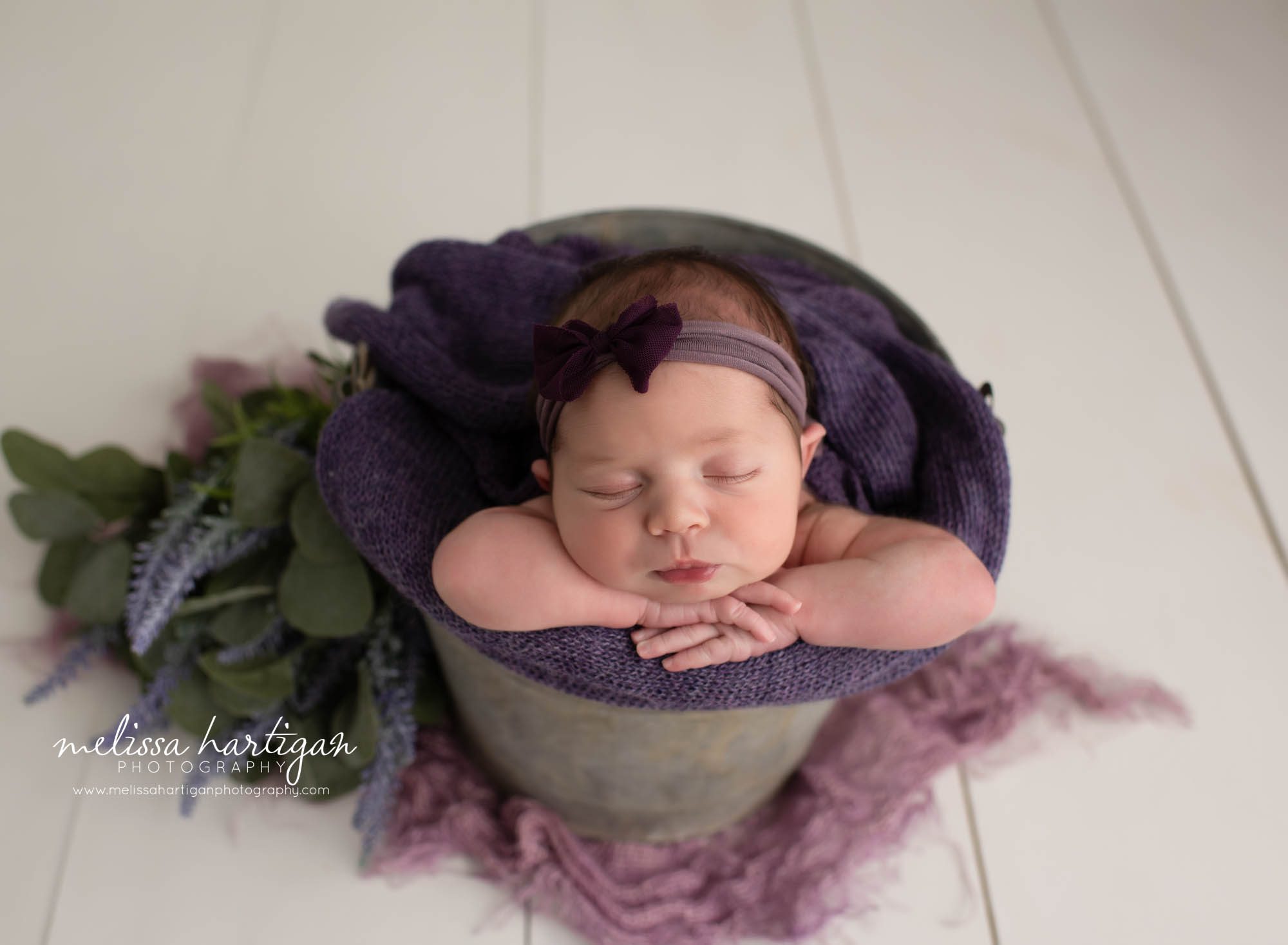 baby girl posed in metal bucket with purple knitted layer and bow headband